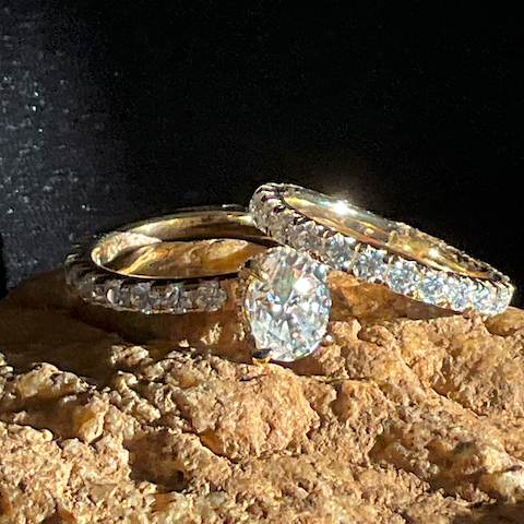 Two diamond rings on a textured surface with a dark background