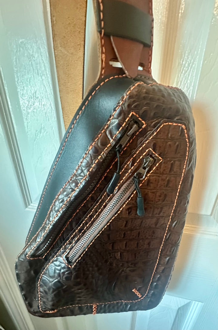 Brown textured bag with a strap against a neutral background