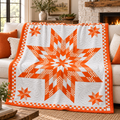 An orange and white quilted throw blanket with a large central star pattern and smaller corner stars, draped over a beige sofa in a cozy living room setting.
