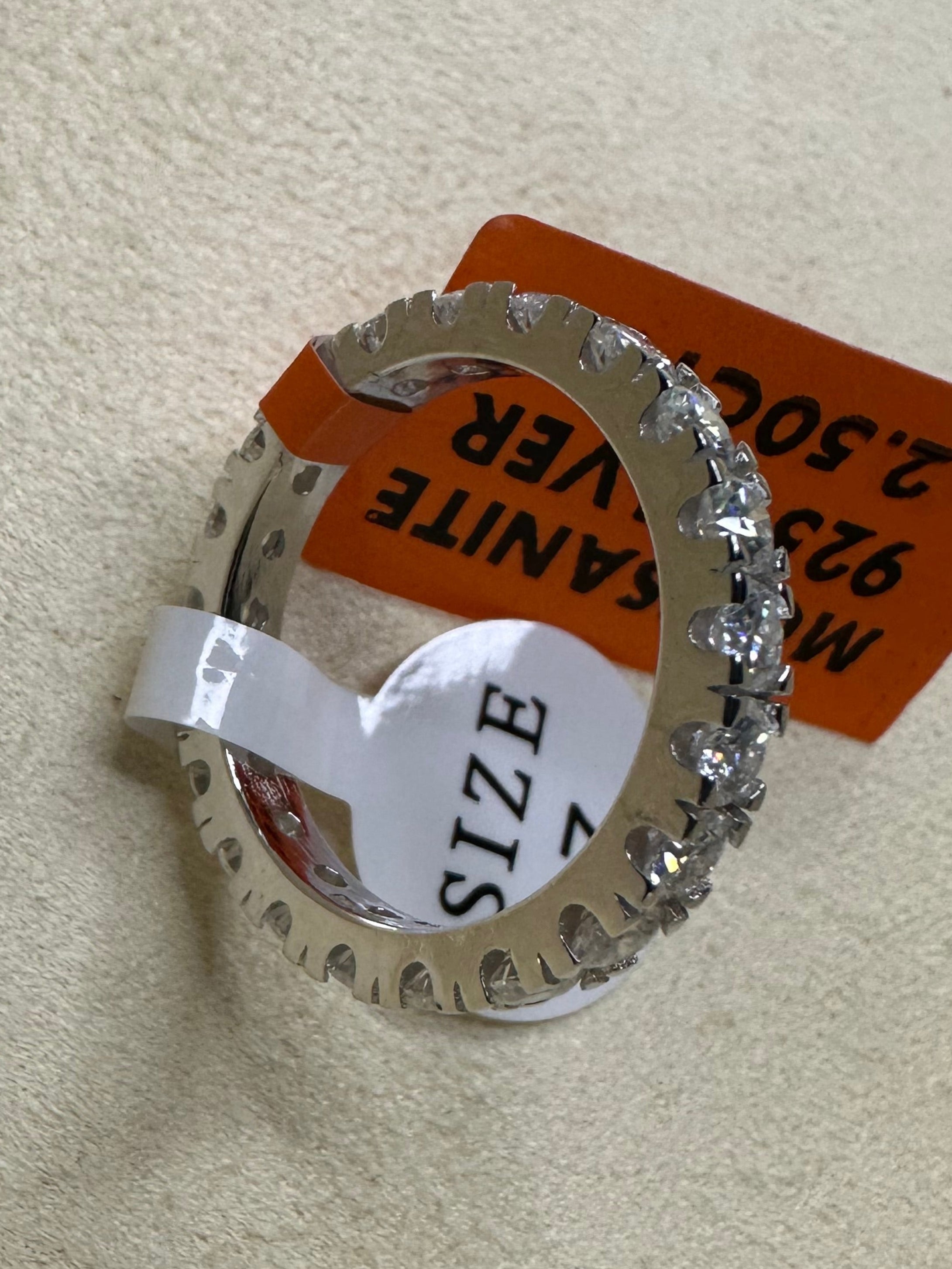 Silver ring with a size label on a beige cushion 