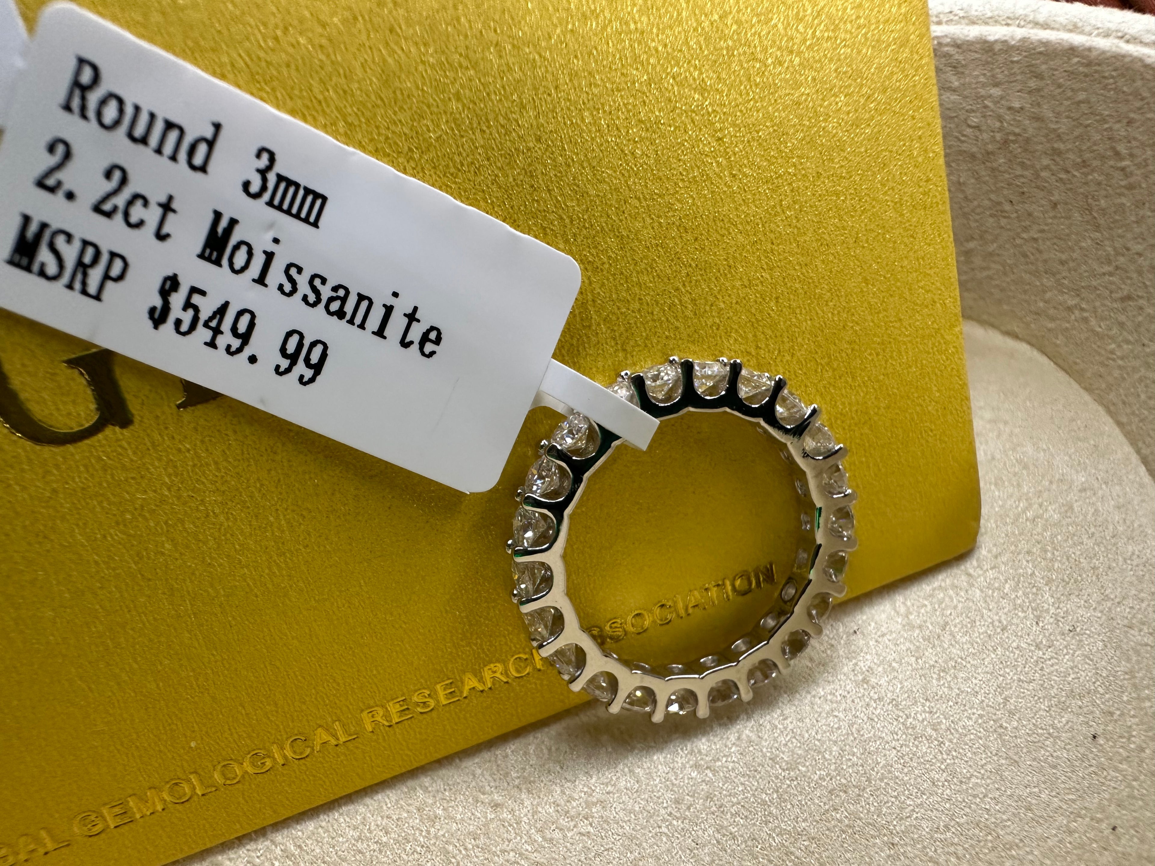 Round 3 mm Moissanite ring with price tag on a gold card