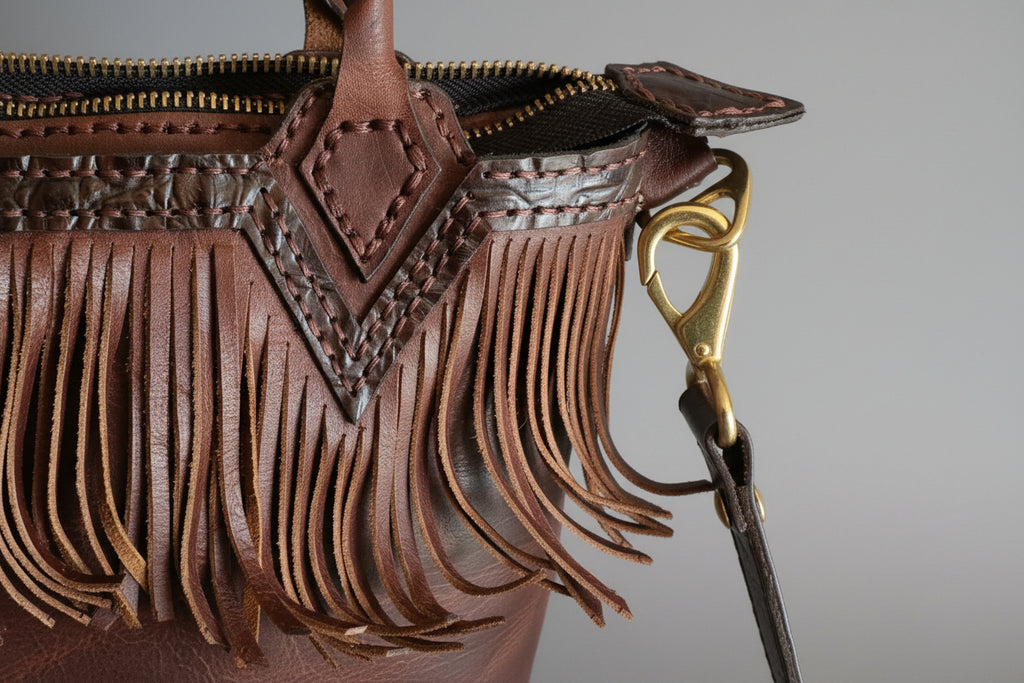 Close-up of a brown leather bag with intricate designs and a gold zipper.