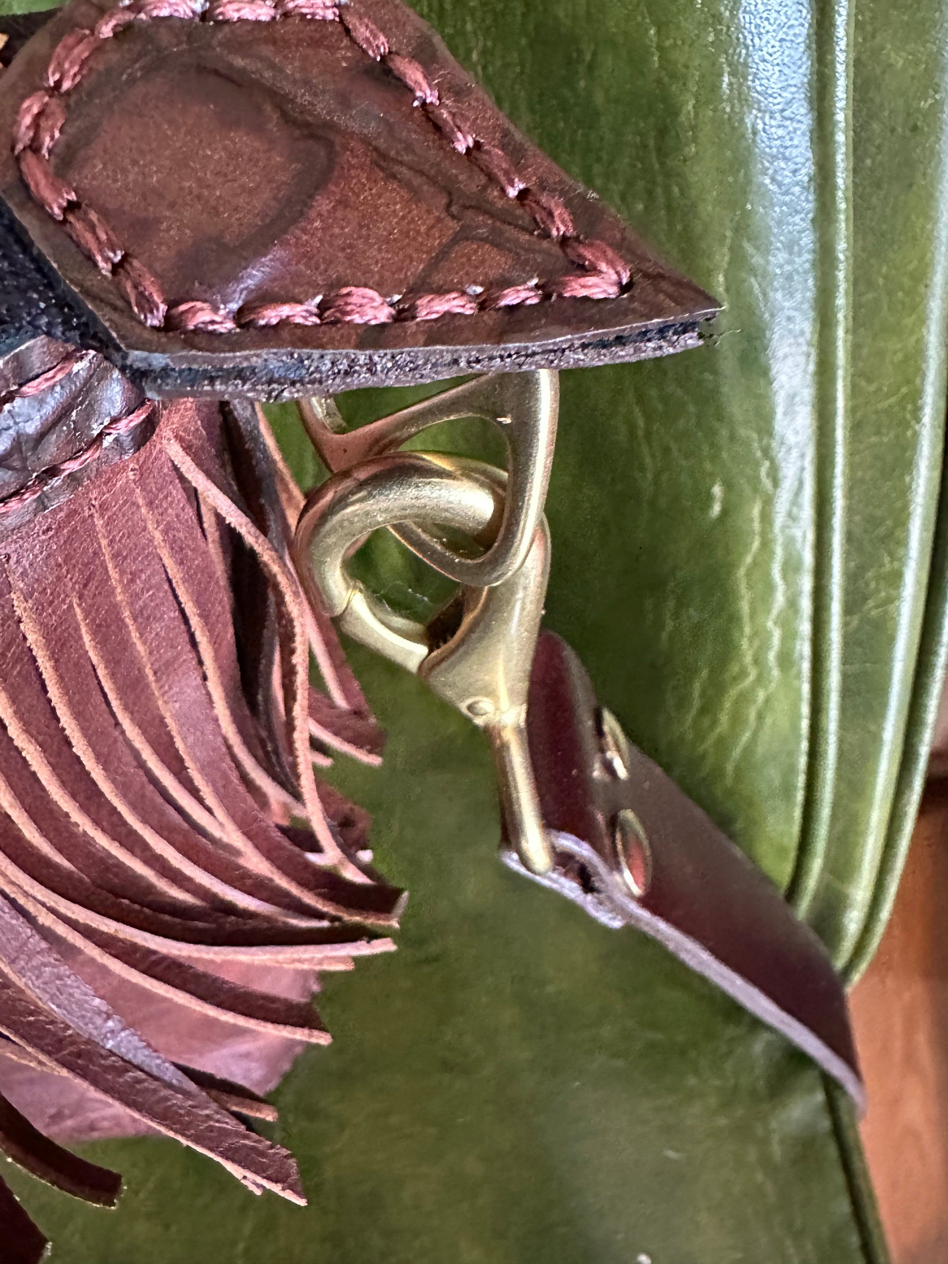 Close-up of a leather strap with a gold buckle on a green background