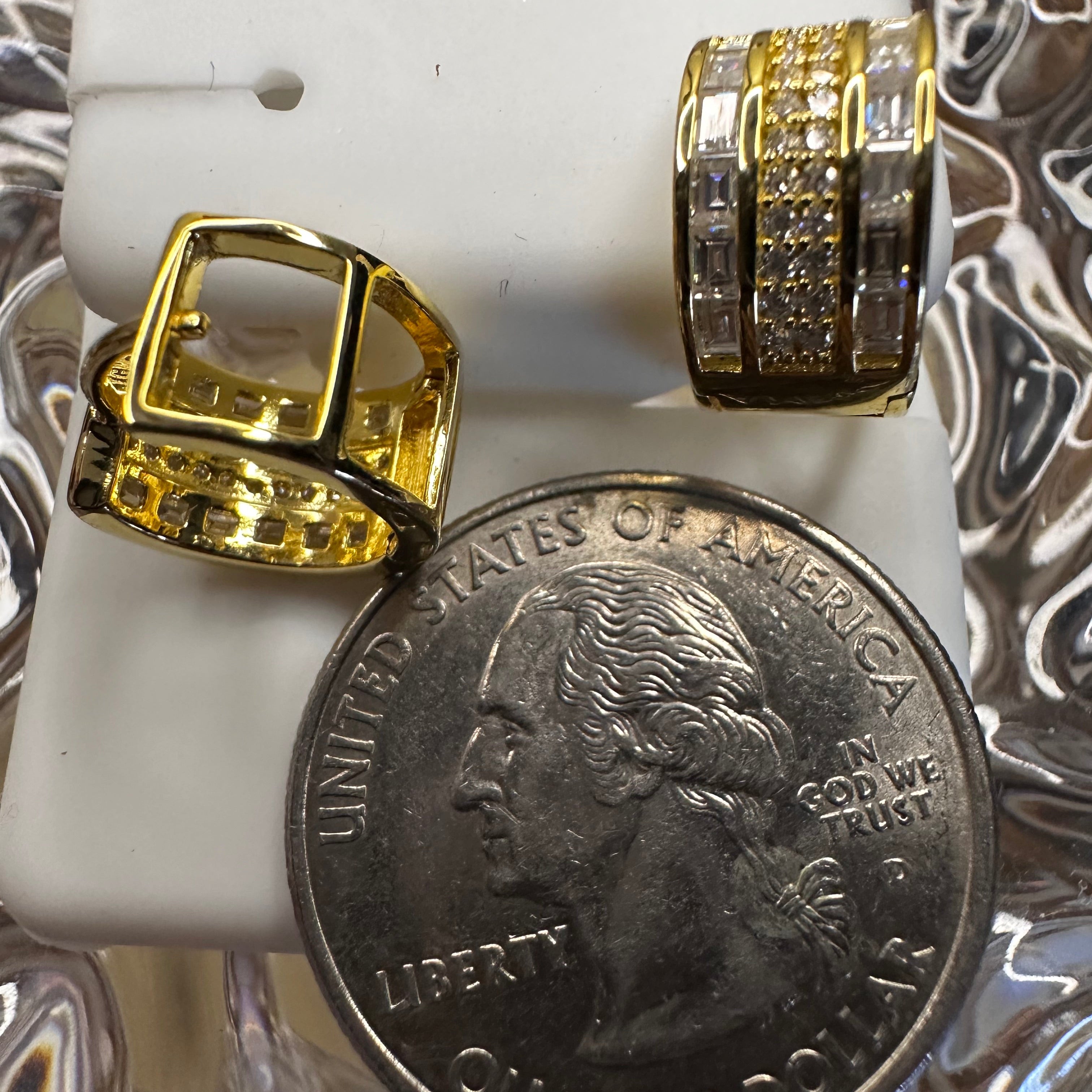 Gold rings displayed next to a quarter on a marble surface