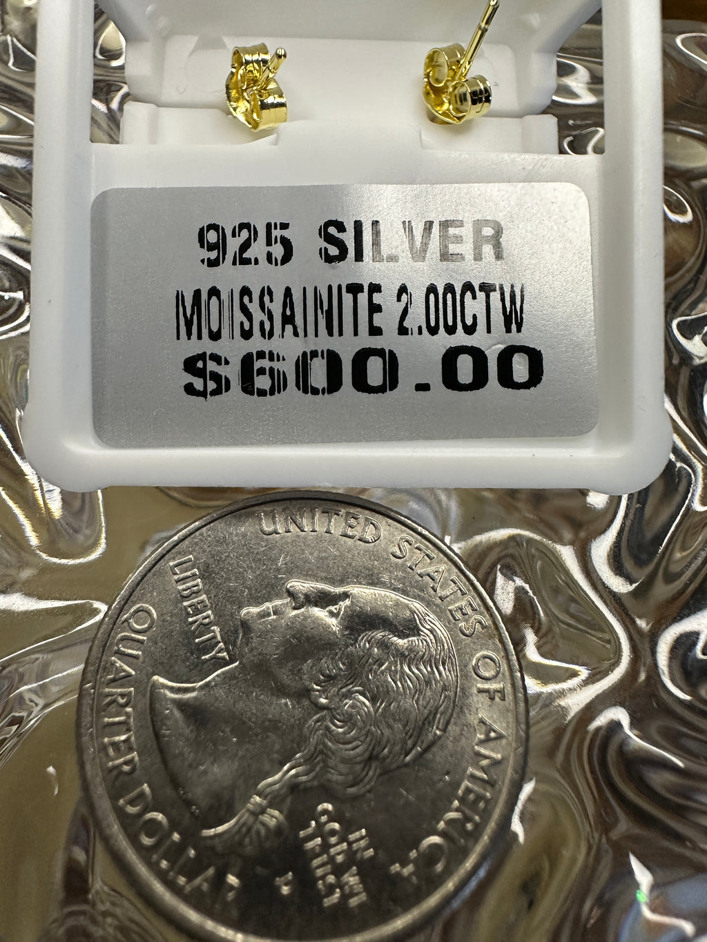 Jewelry display with '925 Silver Moissanite 2.00CTW' label and a quarter coin underneath.