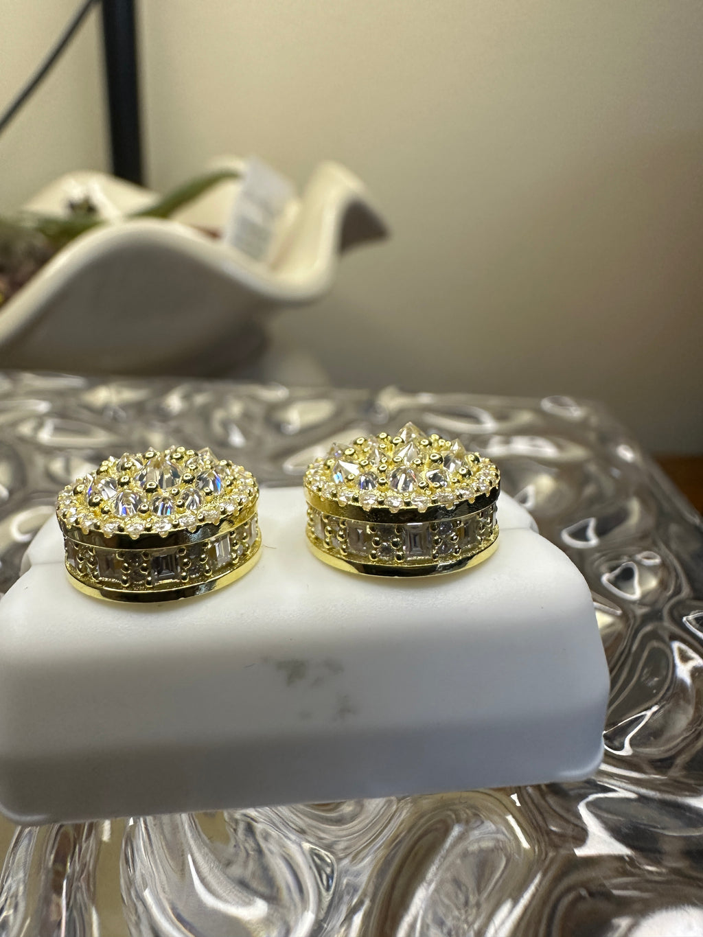 Gold and diamond earrings on a white stand with a blurred background