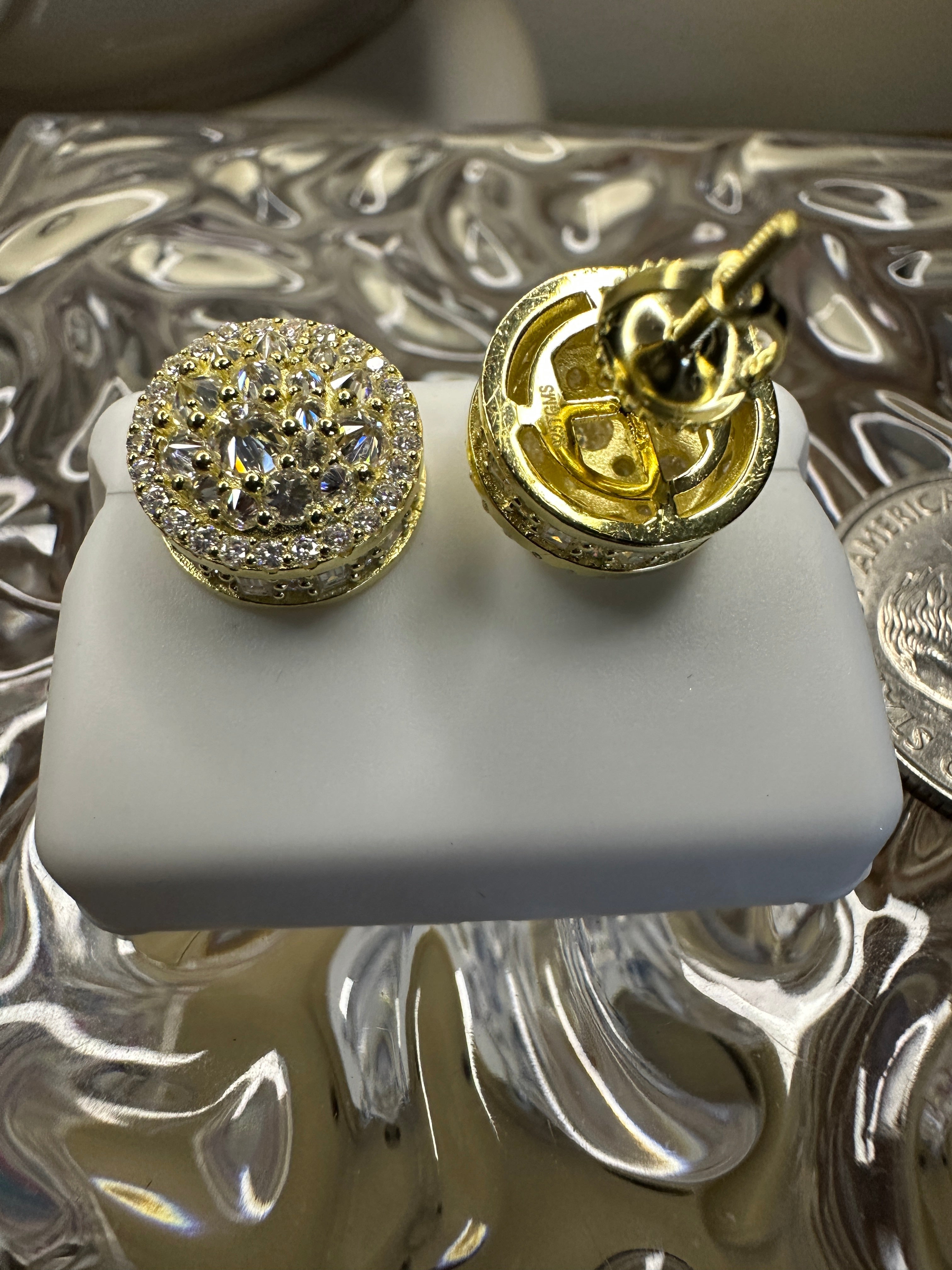 Gold and diamond earrings on a white stand with a decorative background