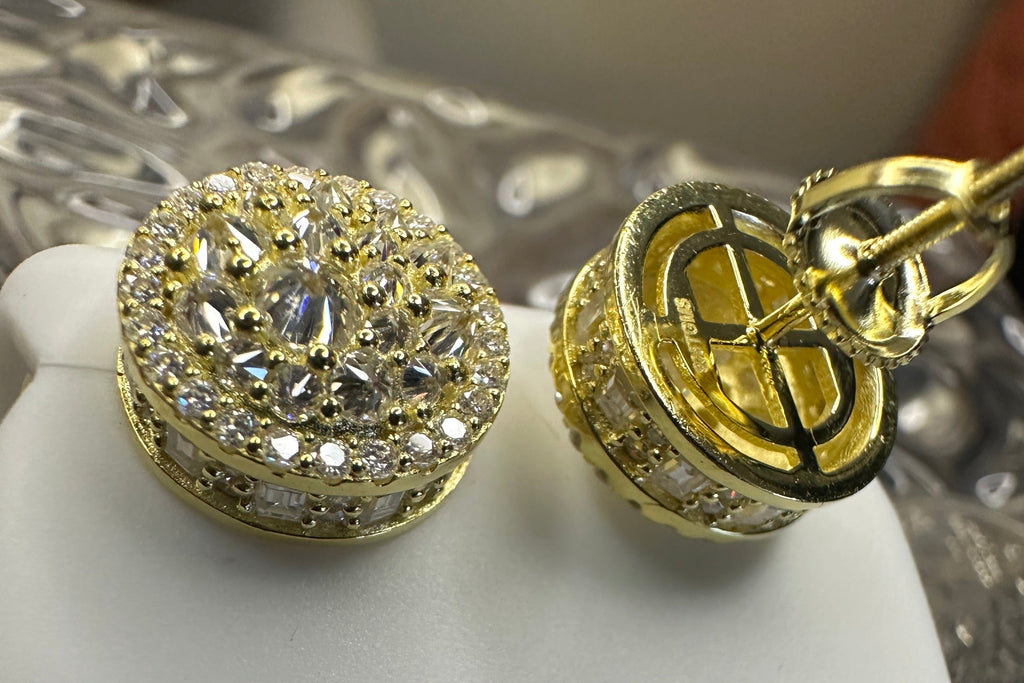 Gold earrings with intricate designs and caged on the back with the makers-mark