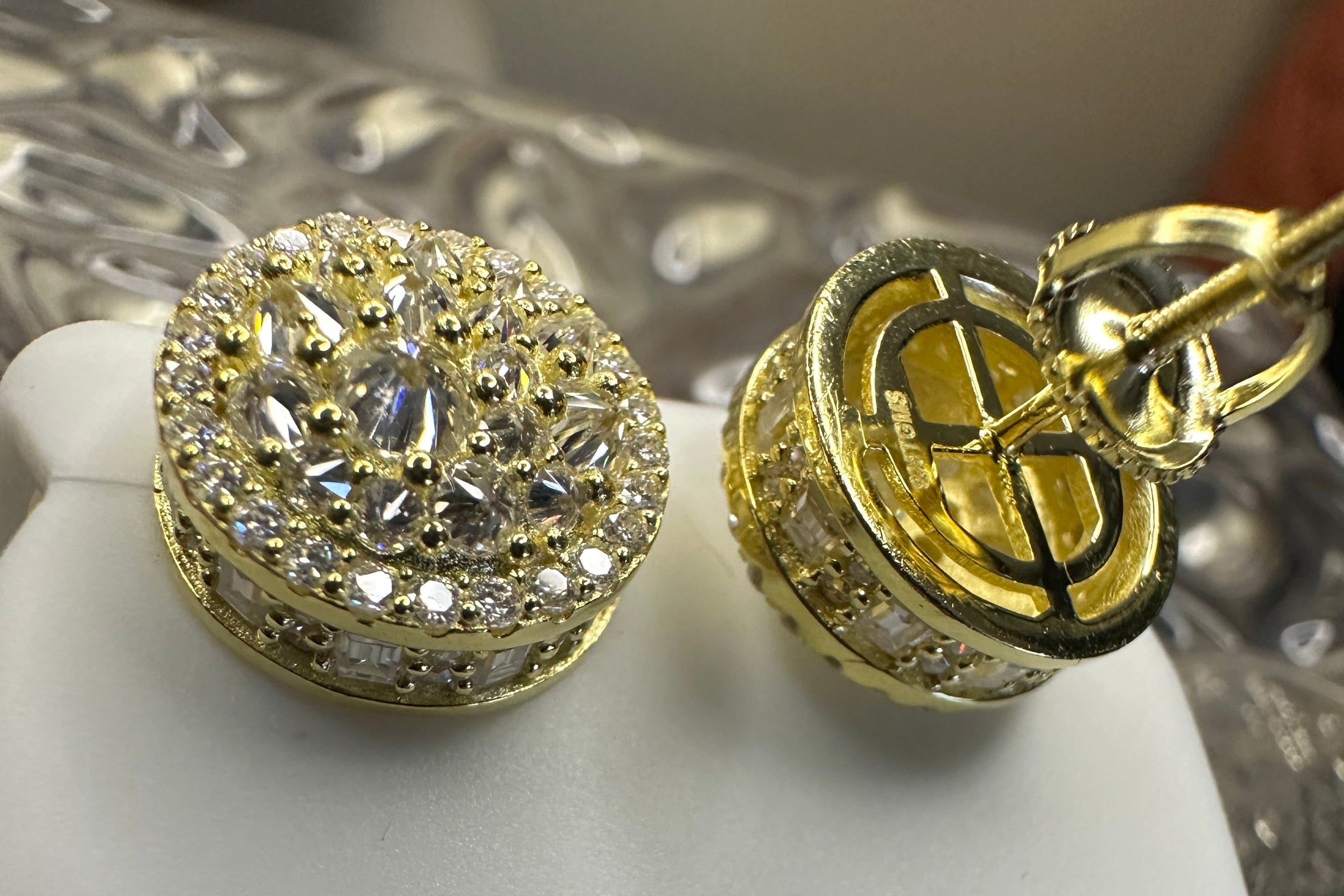 Gold earrings with intricate designs and caged on the back with the makers-mark