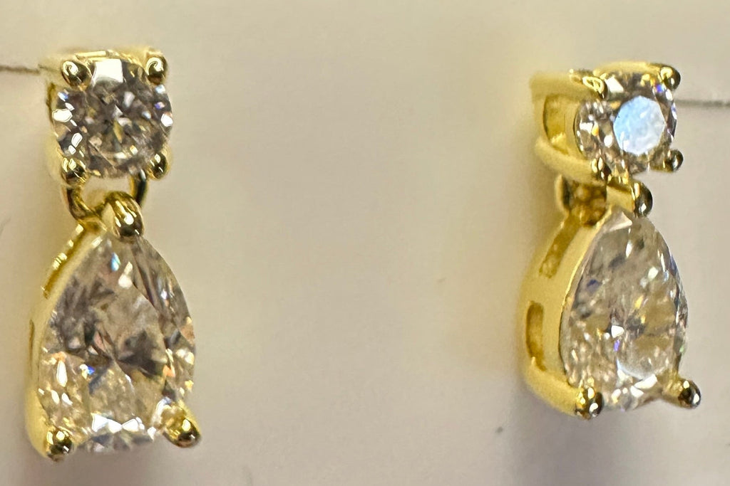 Gold earrings with clear stones on a white jewelry box.