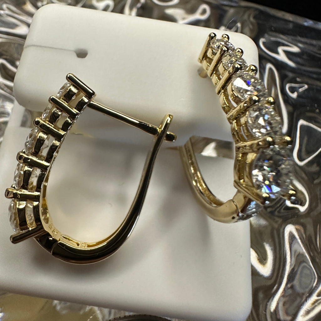 Gold hoop earrings on a white stand with a blurred background