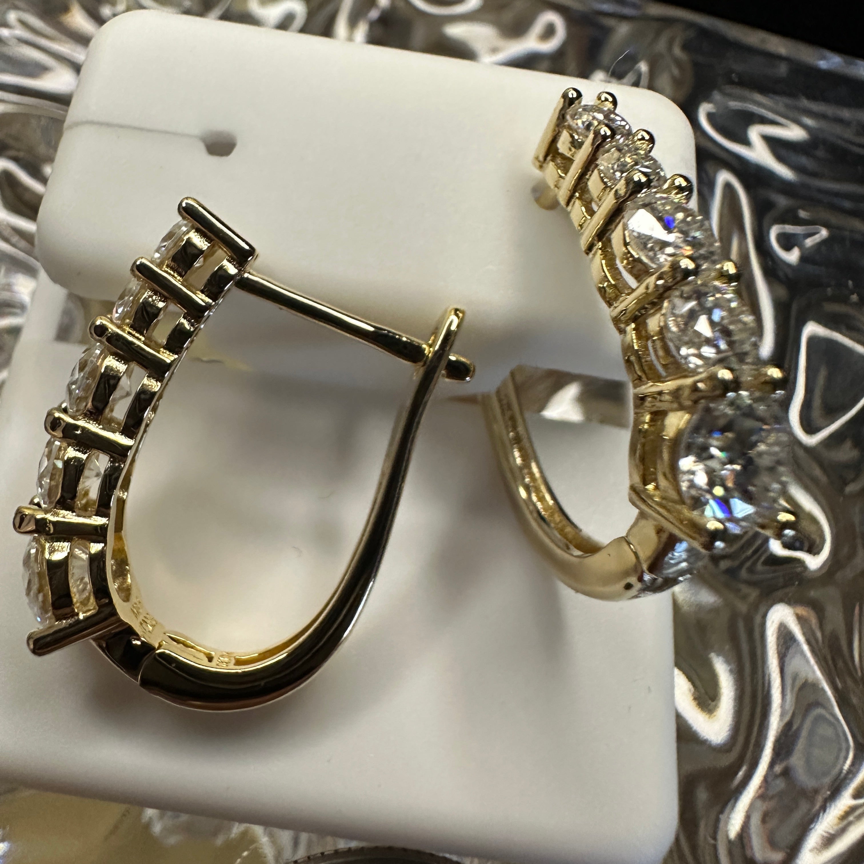 Gold hoop earrings on a white stand with a blurred background