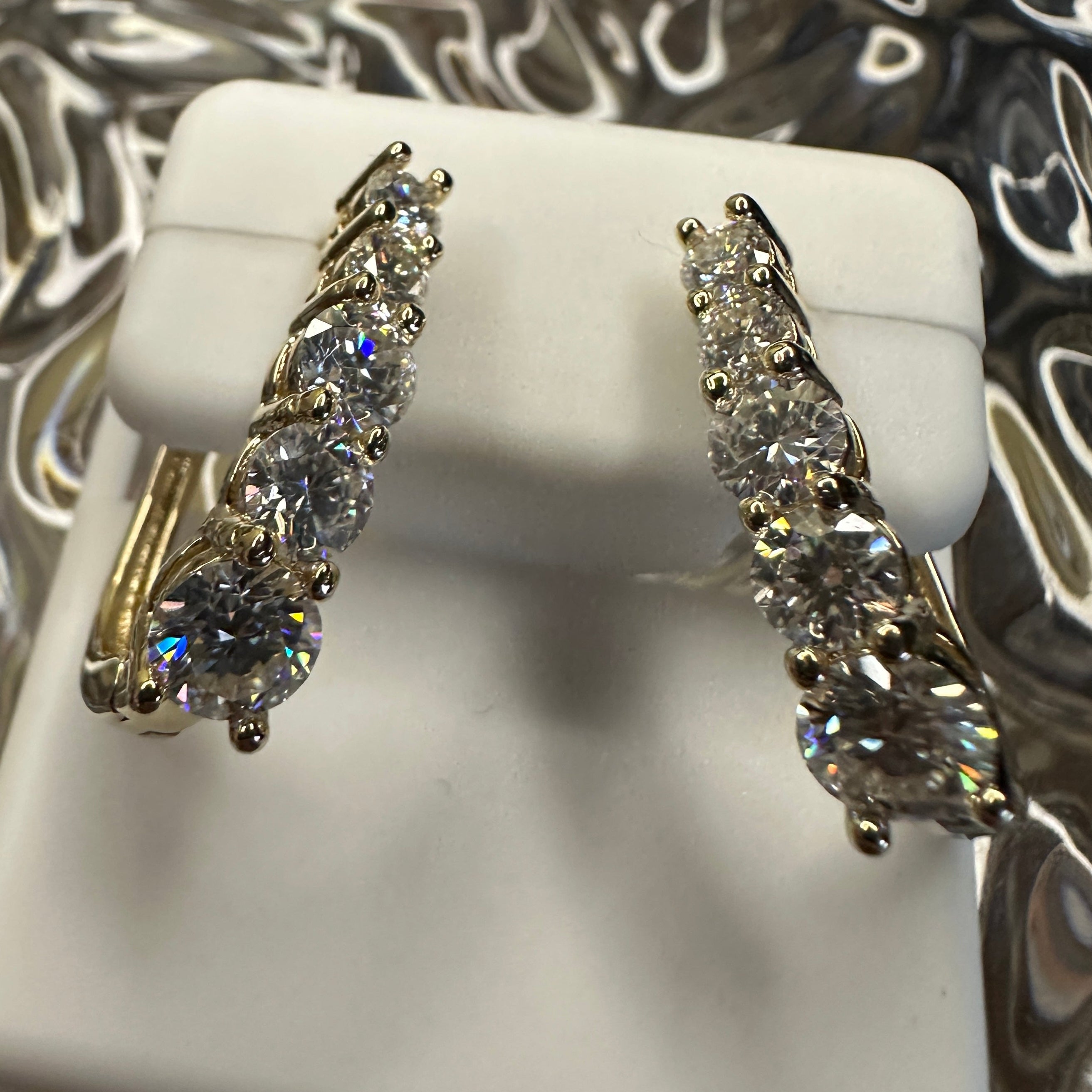 Pair of diamond earrings on a white stand with a decorative background