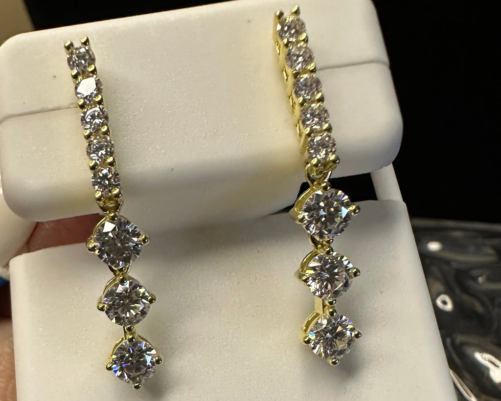 Diamond earrings on a white display card with a quarter for scale, held by a hand.