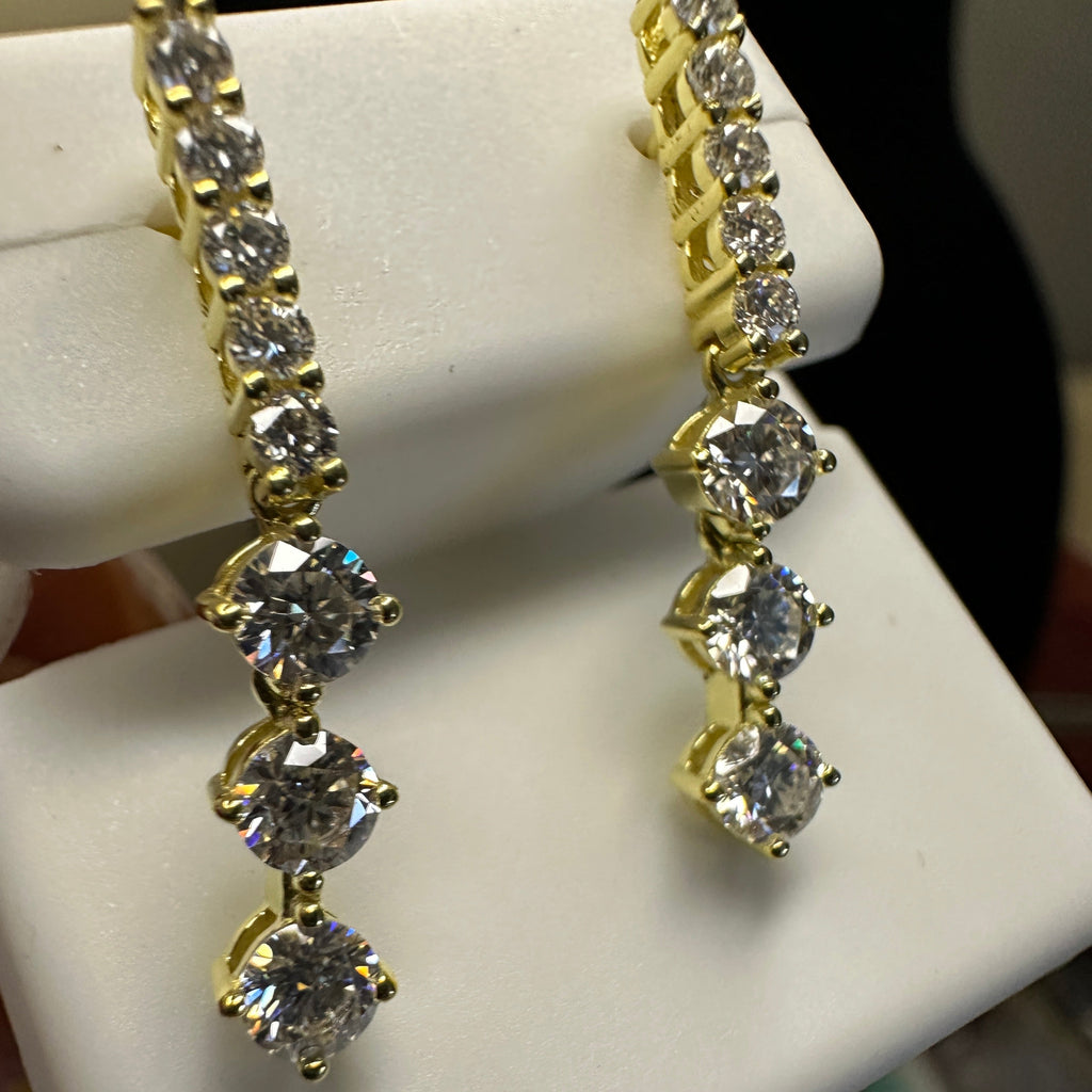 Gold and diamond earrings on a white stand