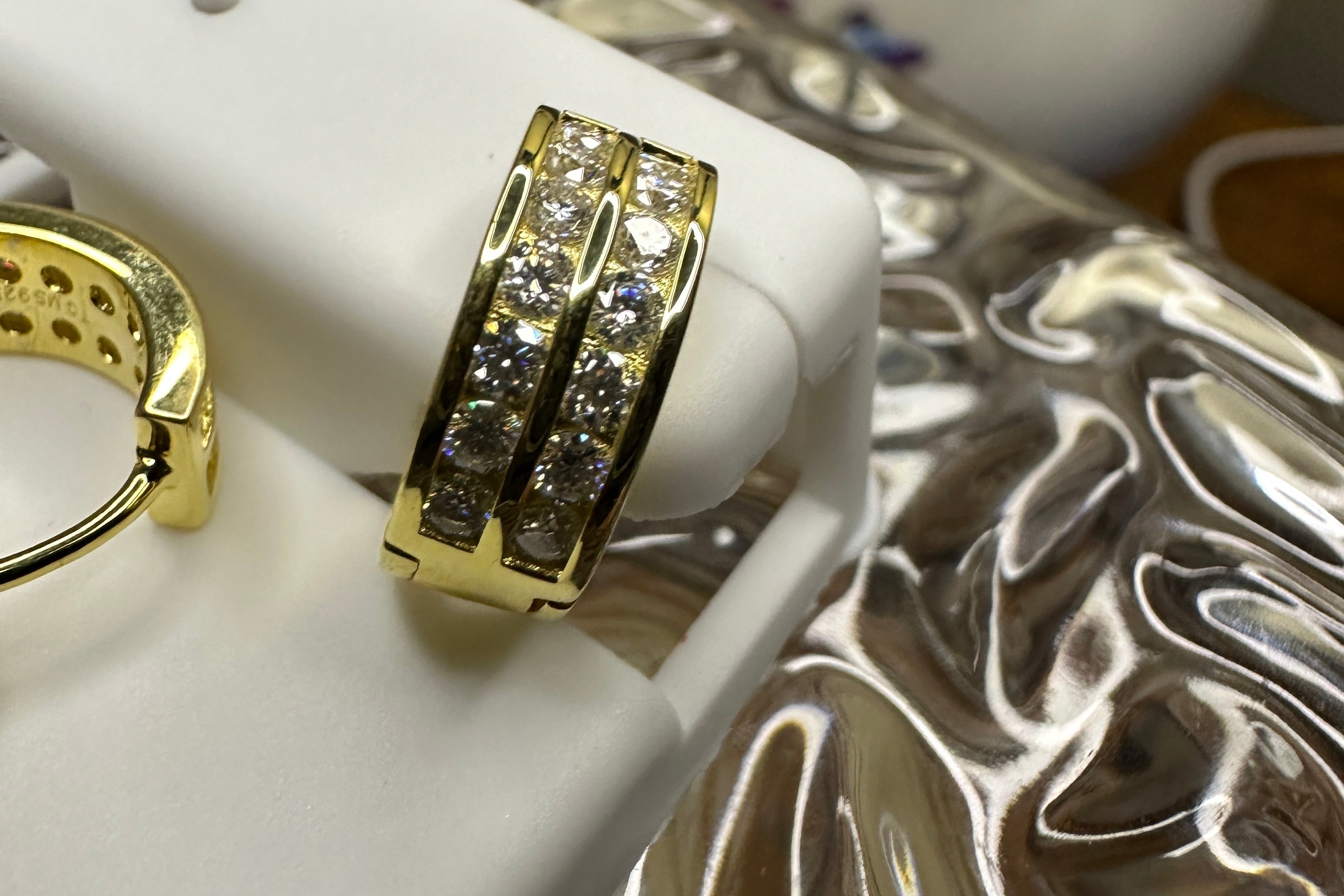 Gold ring with diamonds on a white stand against a decorative background