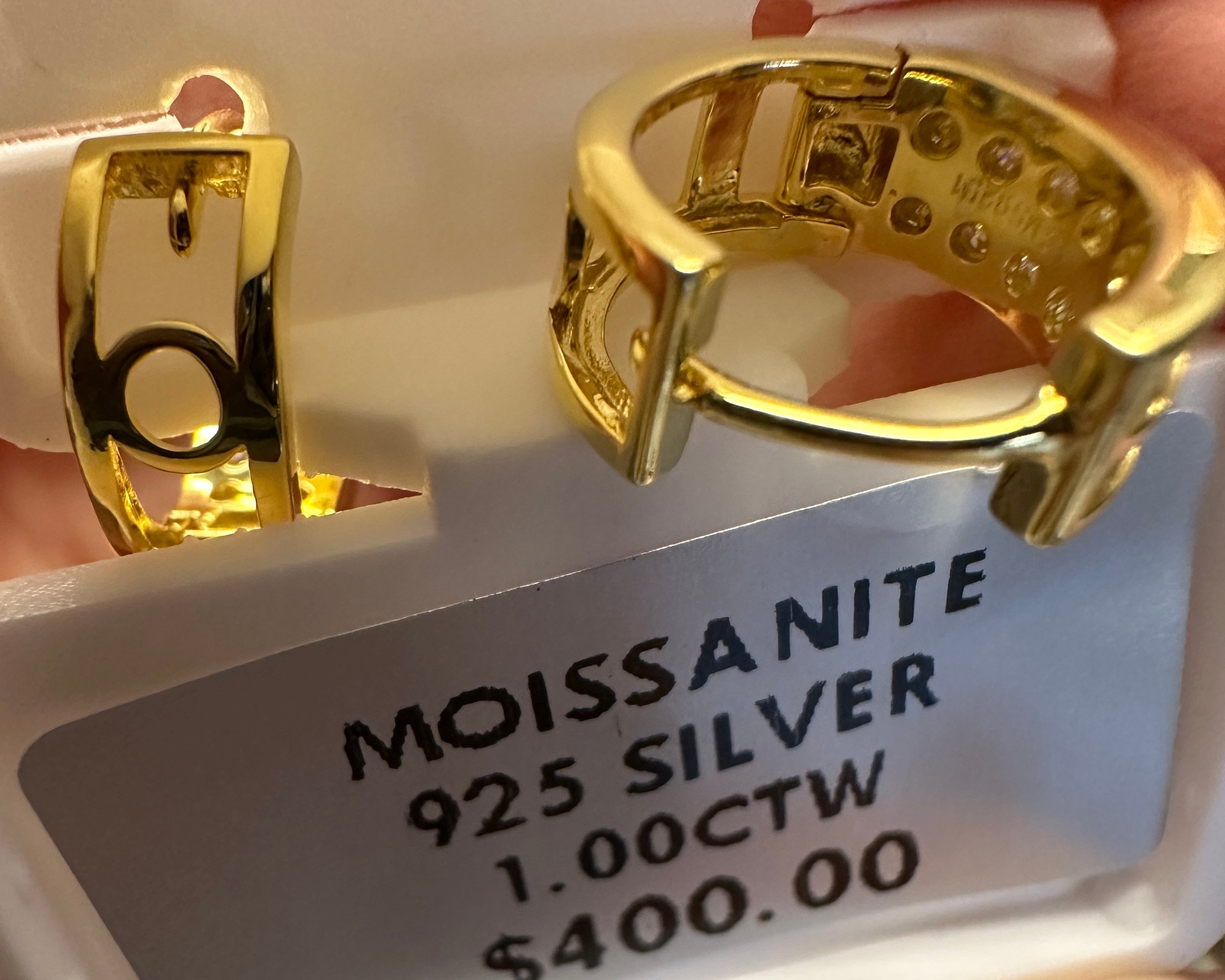 Gold earrings on a display card with 'Moissanite' and '925 Silver' information.