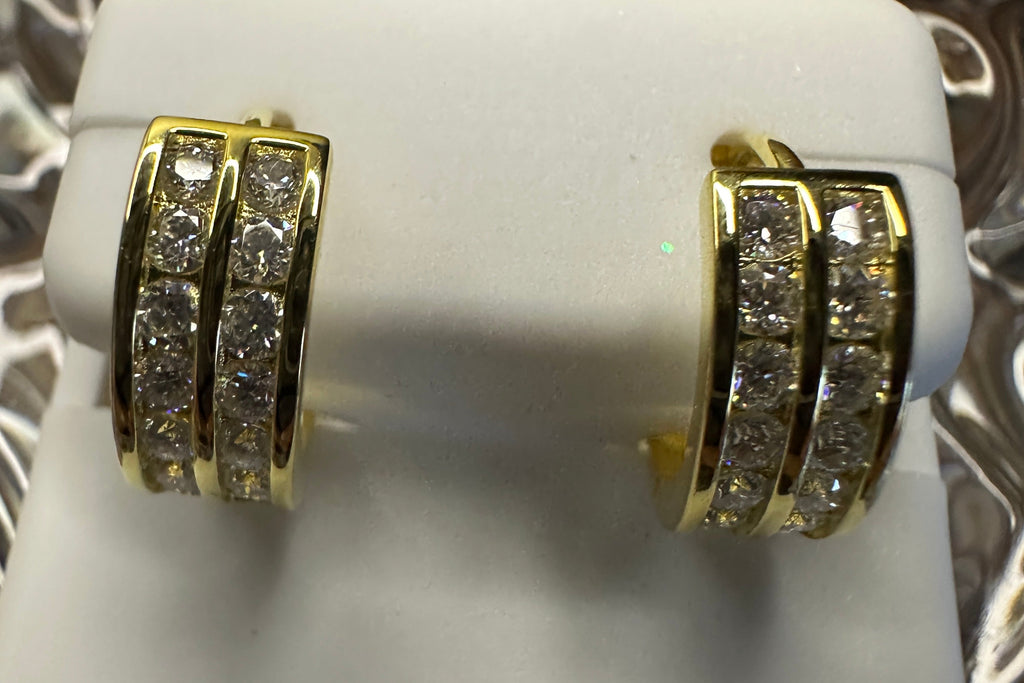 Gold hoop earrings with embedded stones on a white stand.