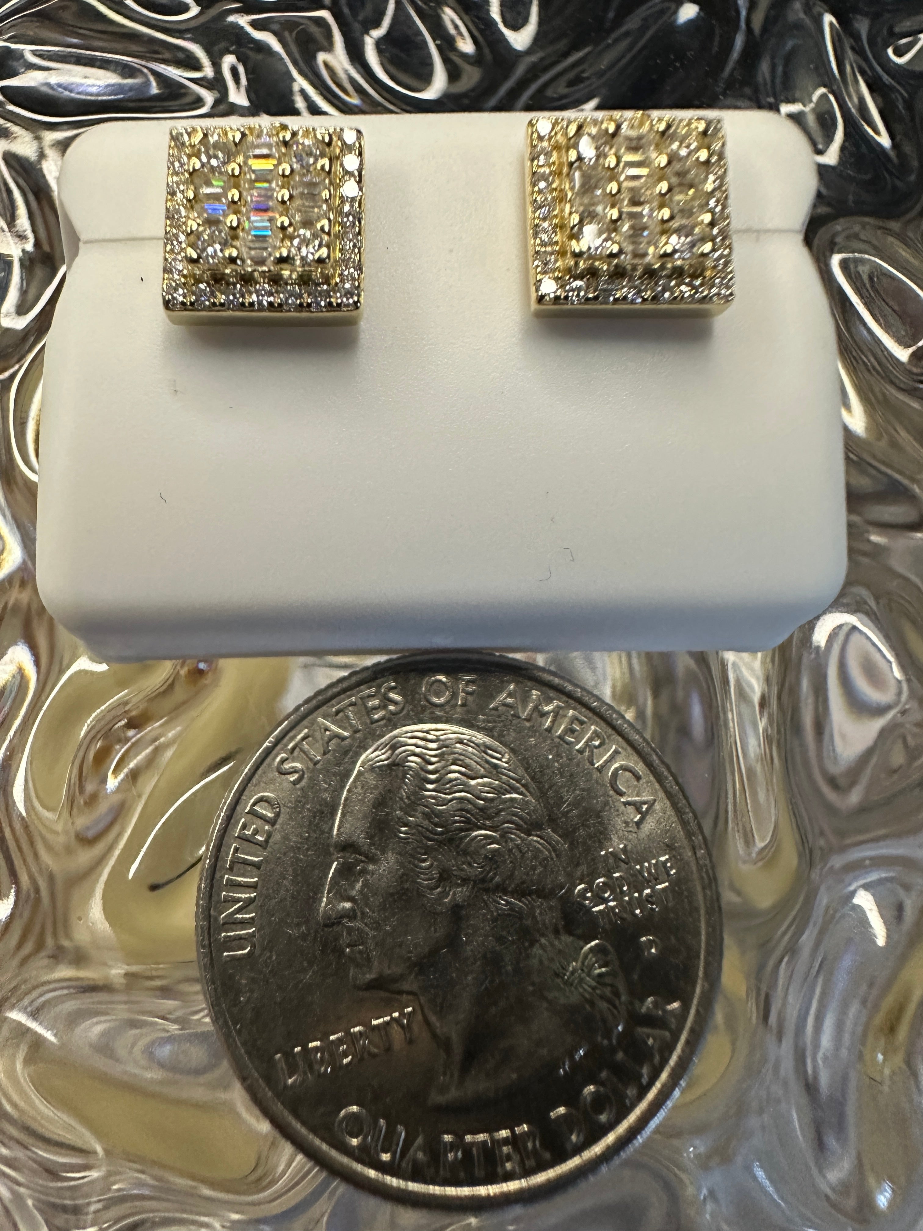 Gold square earrings with clear stones on a white stand, next to a U.S. quarter coin for scale.
