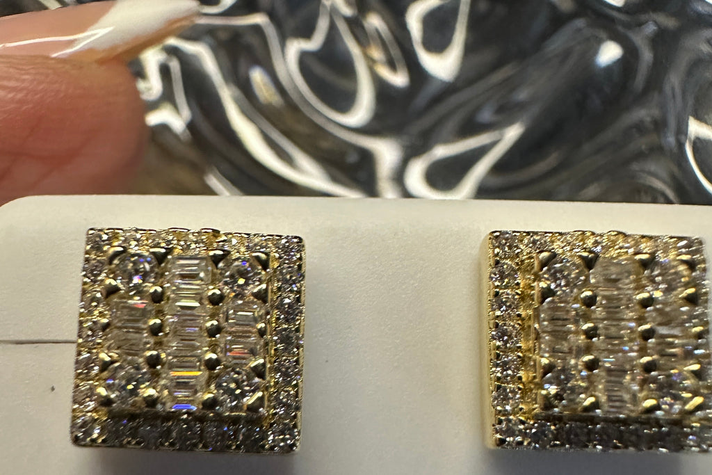 Pair of diamond earrings on a white surface with a blurred background
