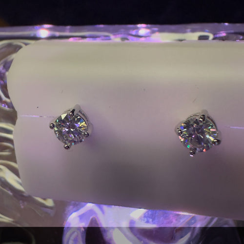 Diamond stud earrings on a white stand with a colorful background