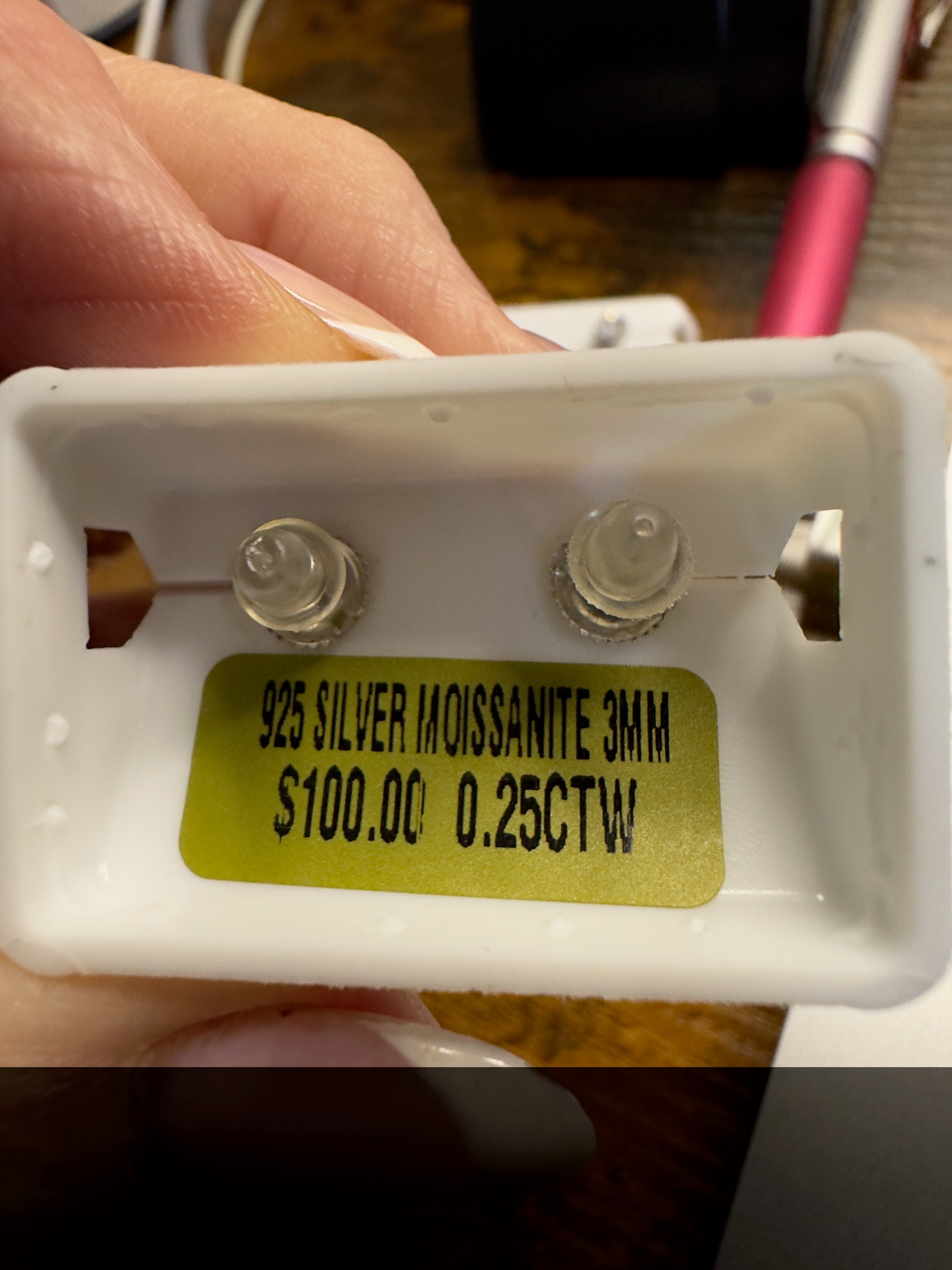 Small jewelry component with '925 Silver Moissanite 3mm' label held by a hand.