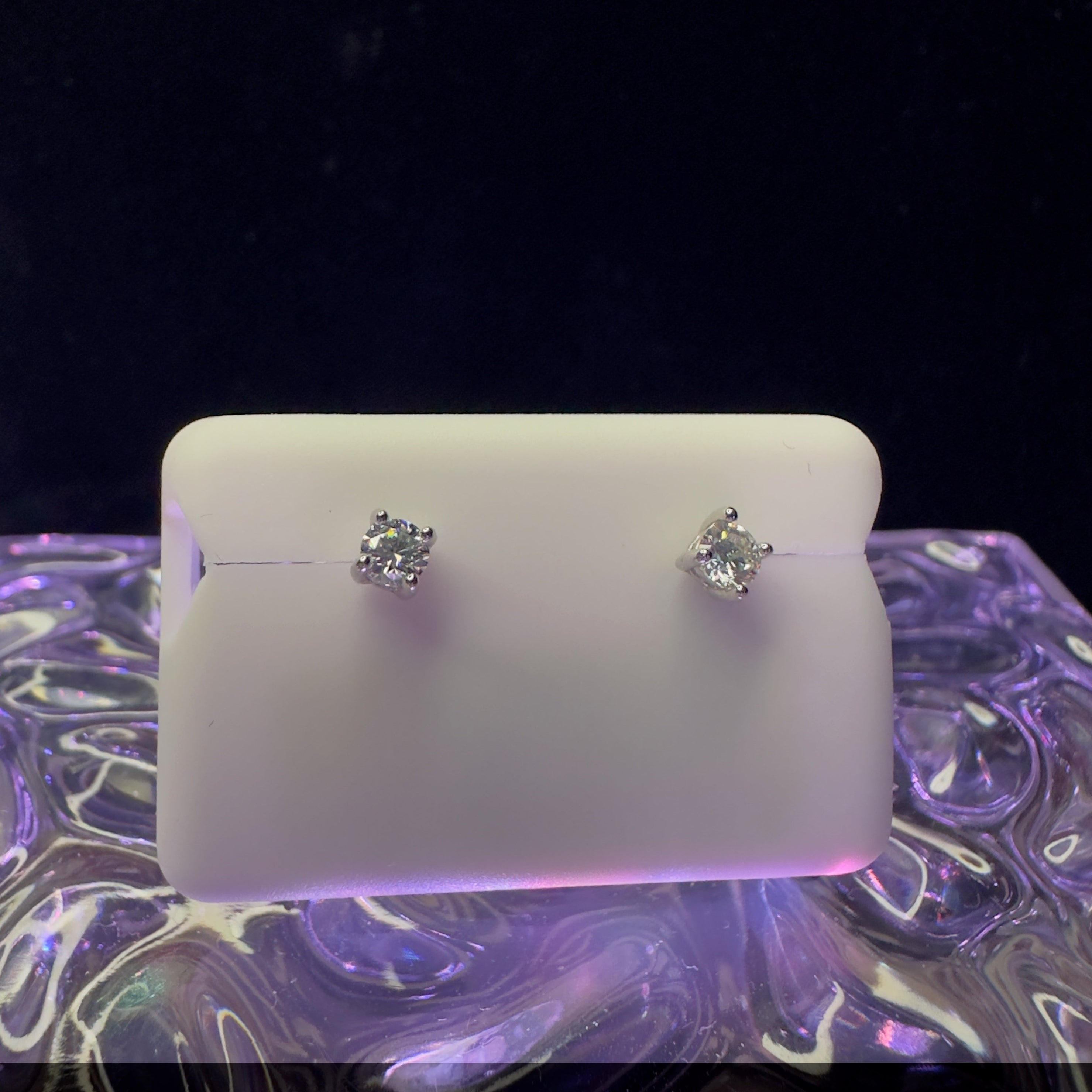 Pair of silver earrings on a white card with a dark background