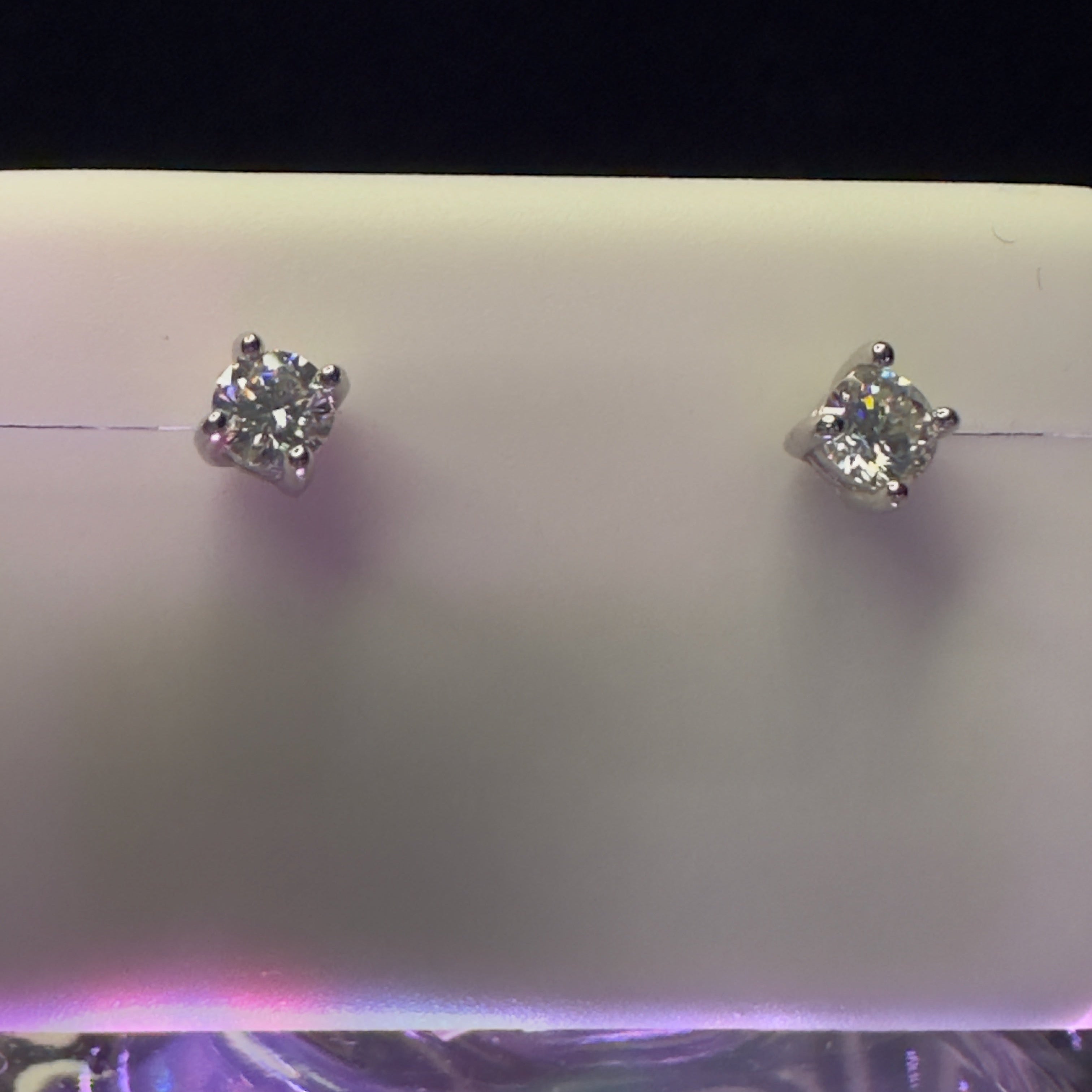 Pair of diamond stud earrings on a light purple background