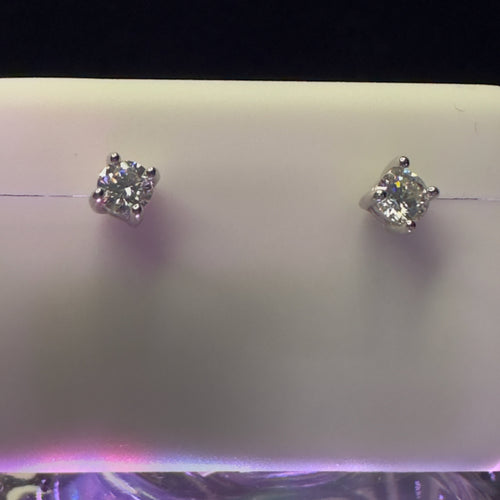 Pair of diamond stud earrings on a light purple background