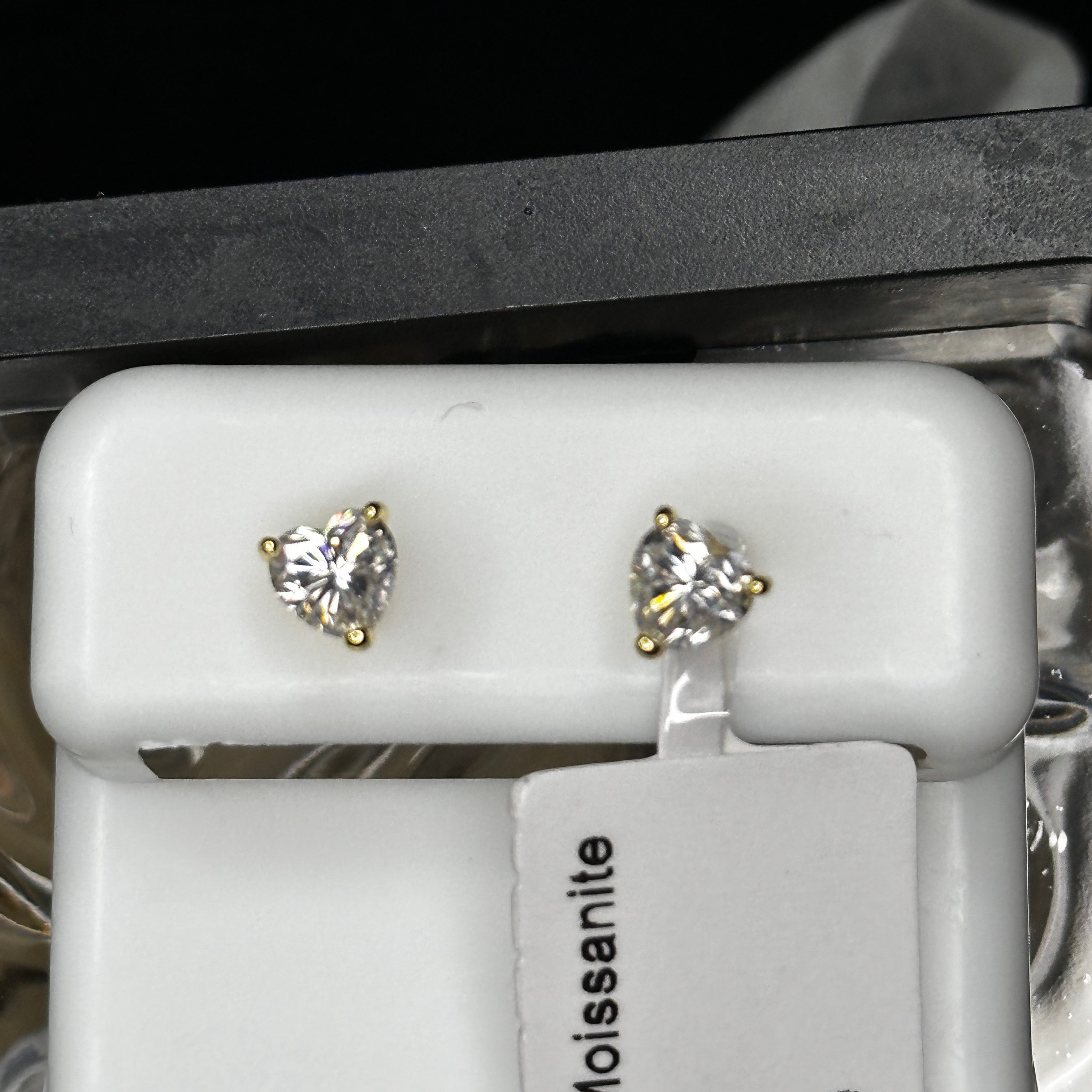 Diamond stud earrings on a white stand with a black background