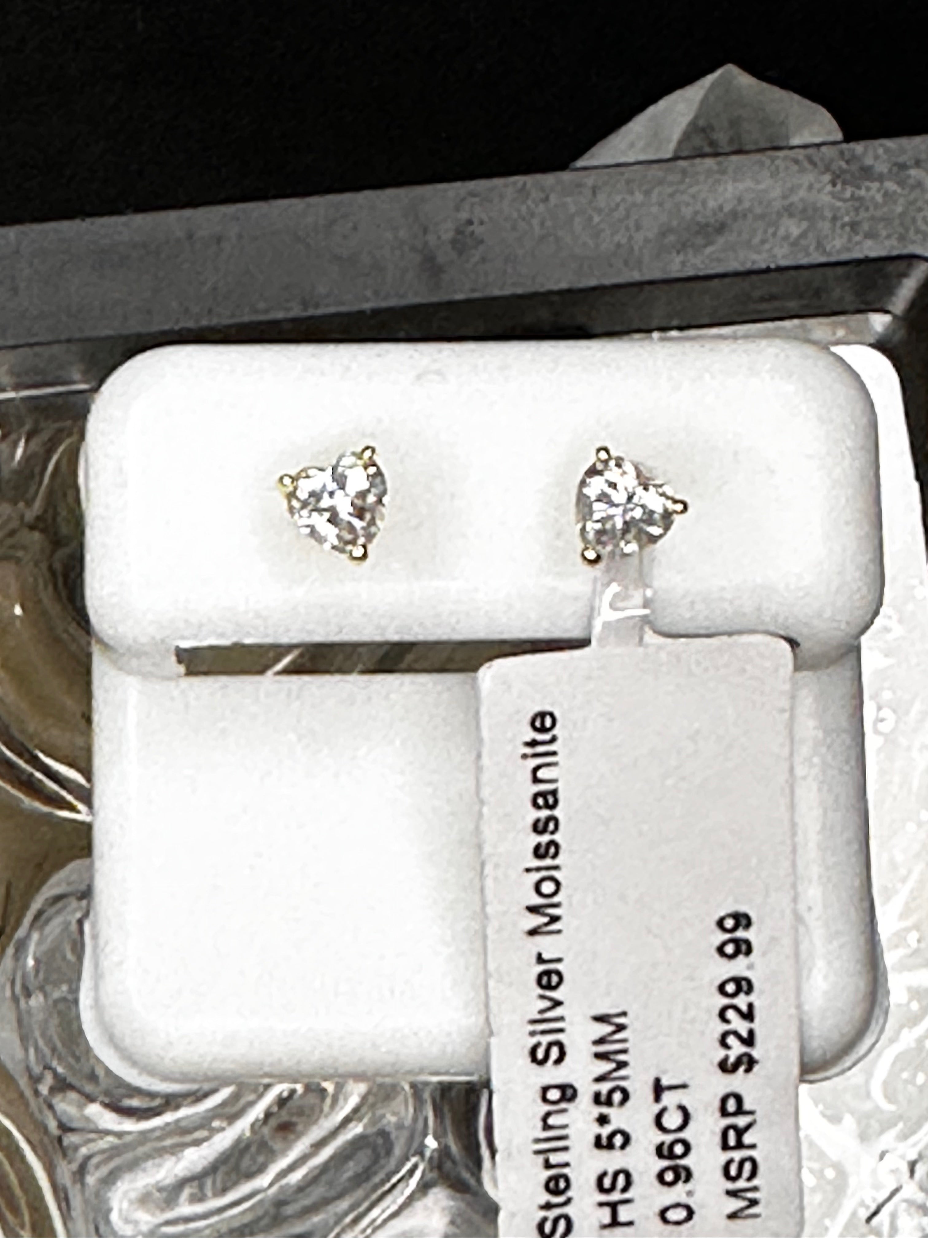 Pair of heart-shaped silver earrings with clear gemstones on a white card.