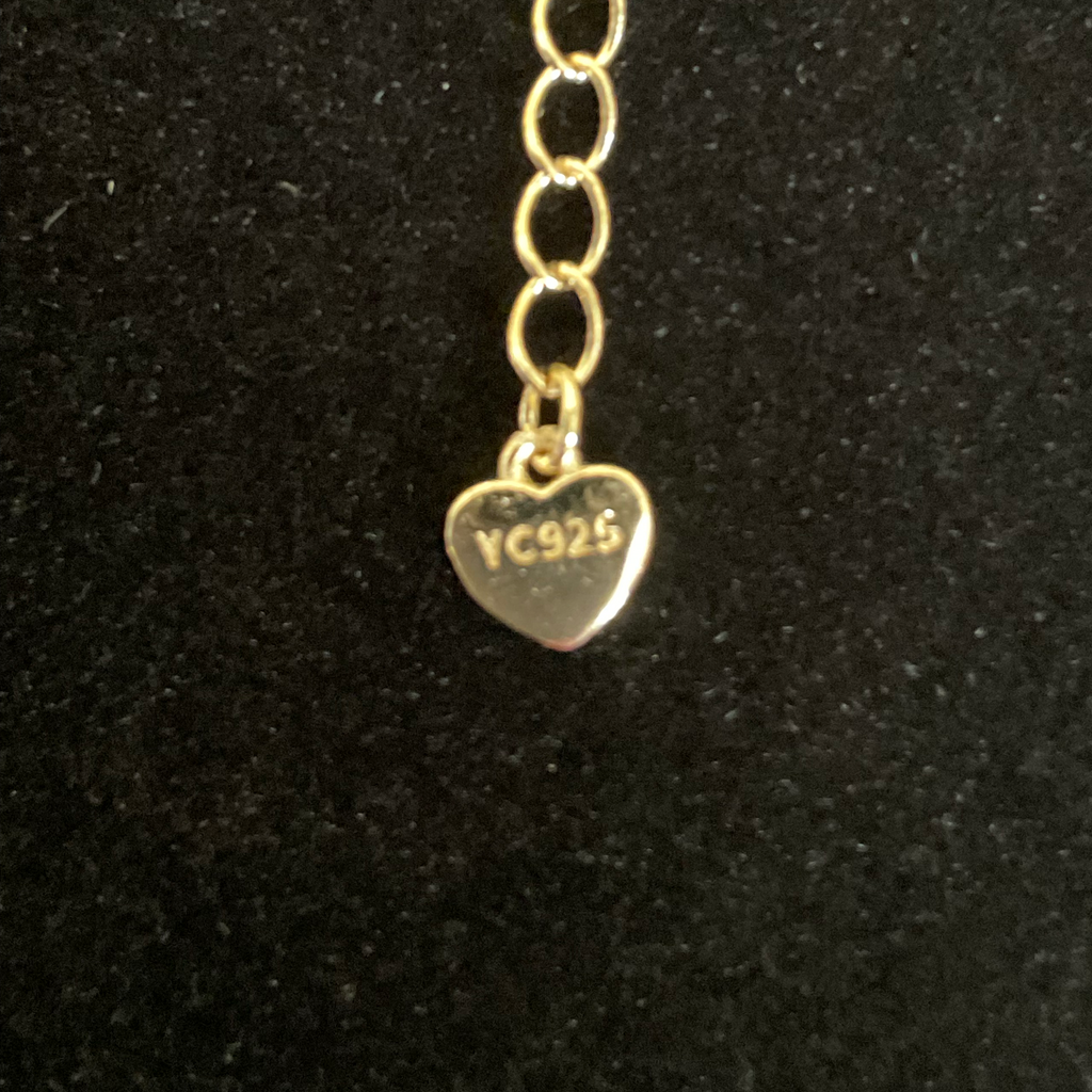 Gold heart-shaped charm with 'YC925' engraving on a black background