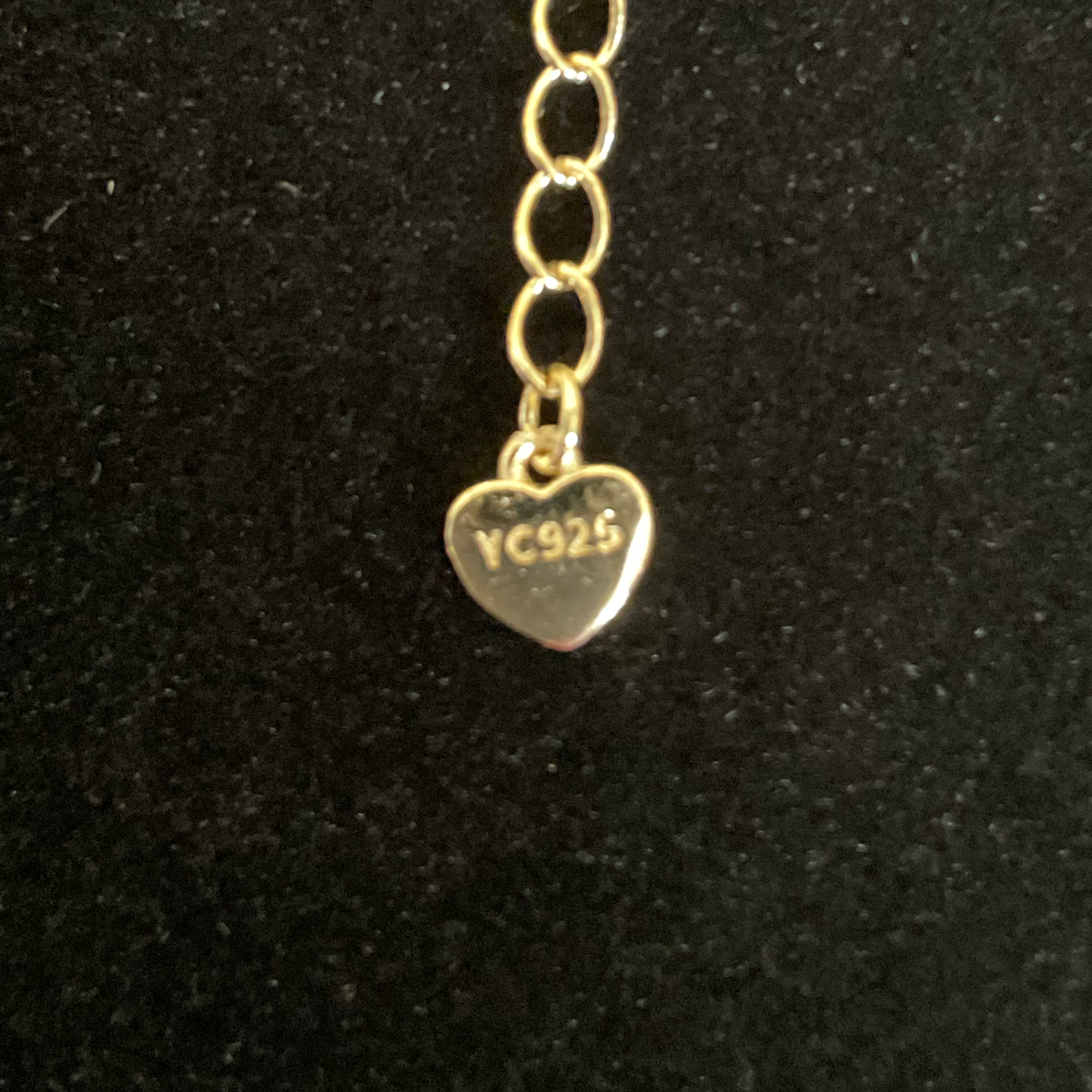 Gold heart-shaped charm with 'YC925' engraving on a black background