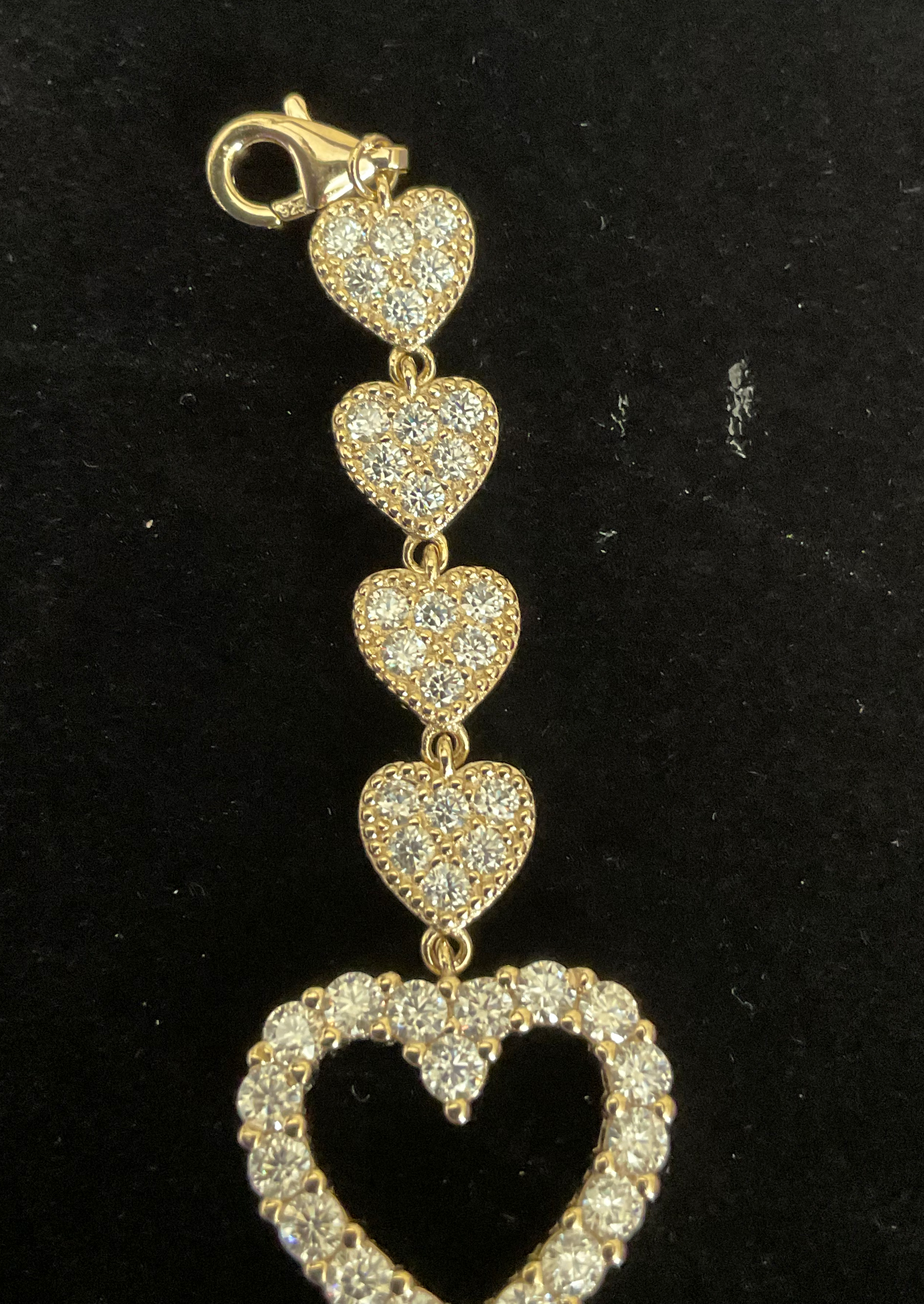 Gold heart-shaped pendant with clear stones on a black background