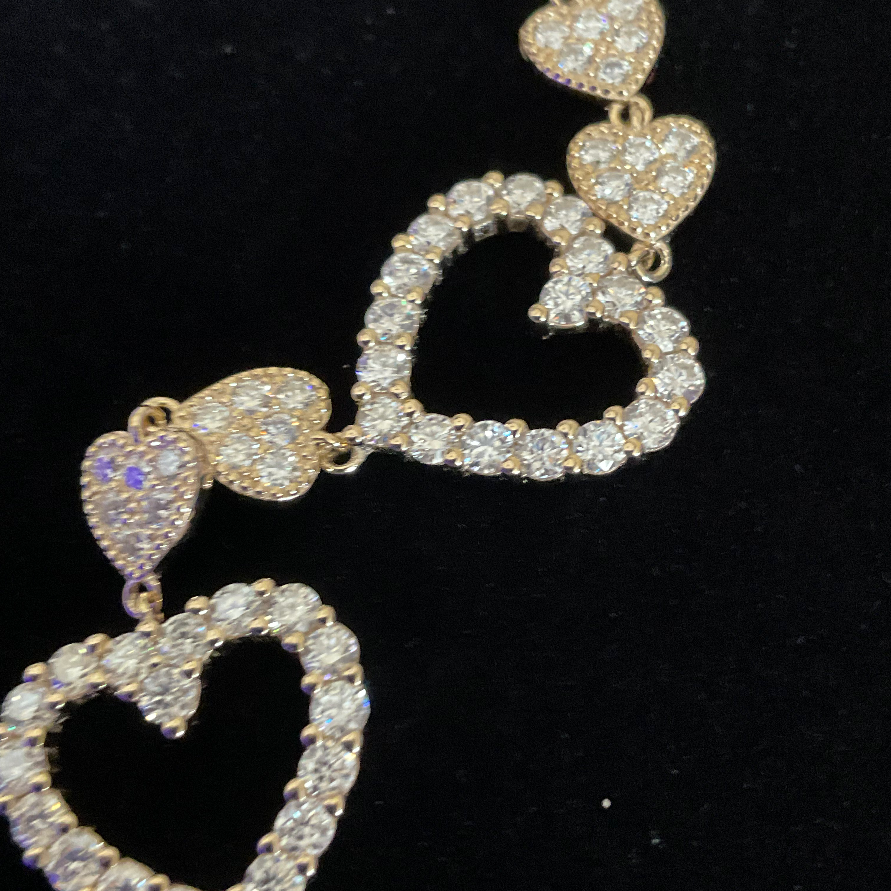 Gold necklace with heart-shaped pendants on a black background