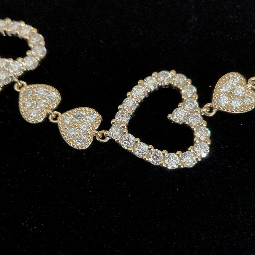 Gold bracelet with heart-shaped links on a black background