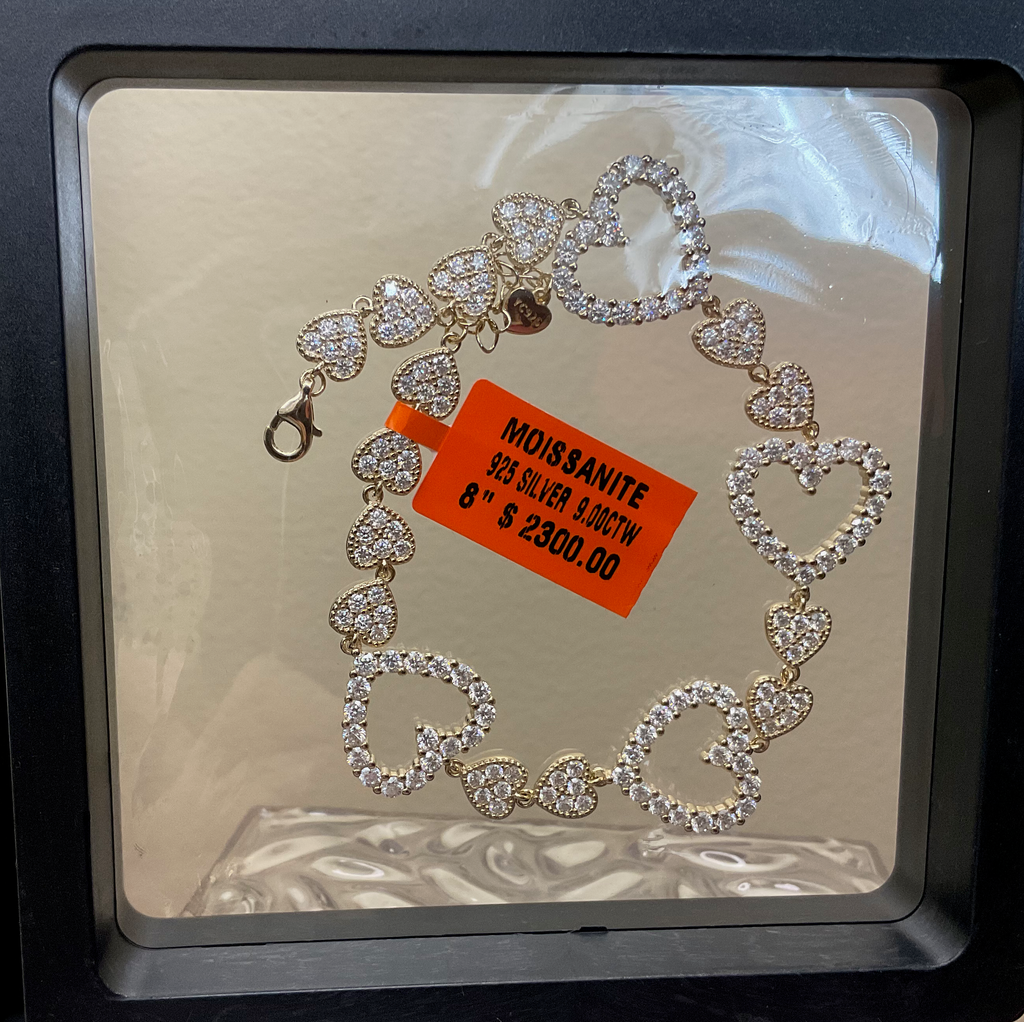 Heart-shaped bracelet with moissanite stones on a reflective surface