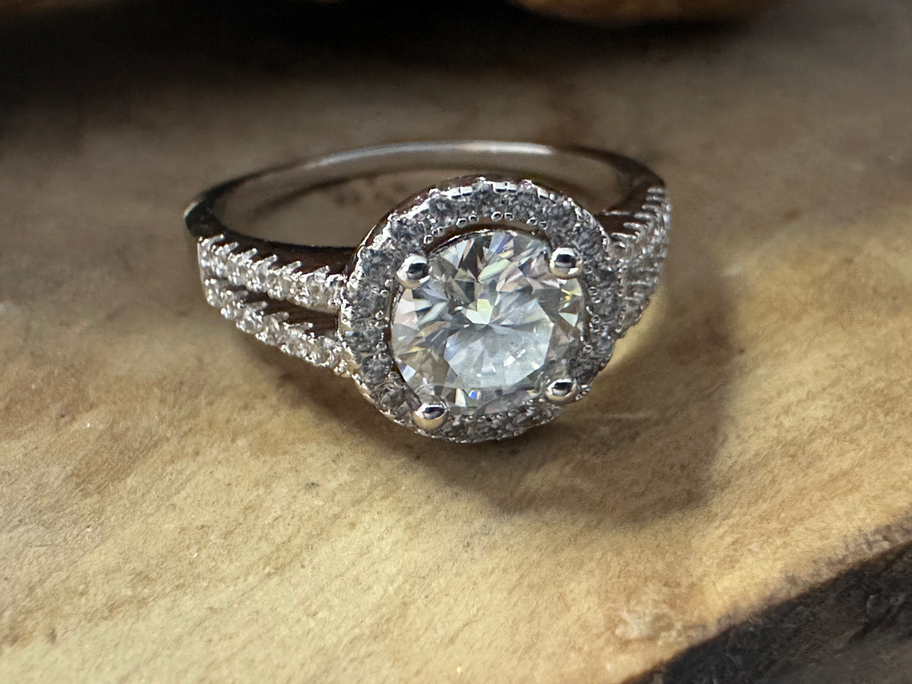 Silver ring with a large diamond on a wooden surface
