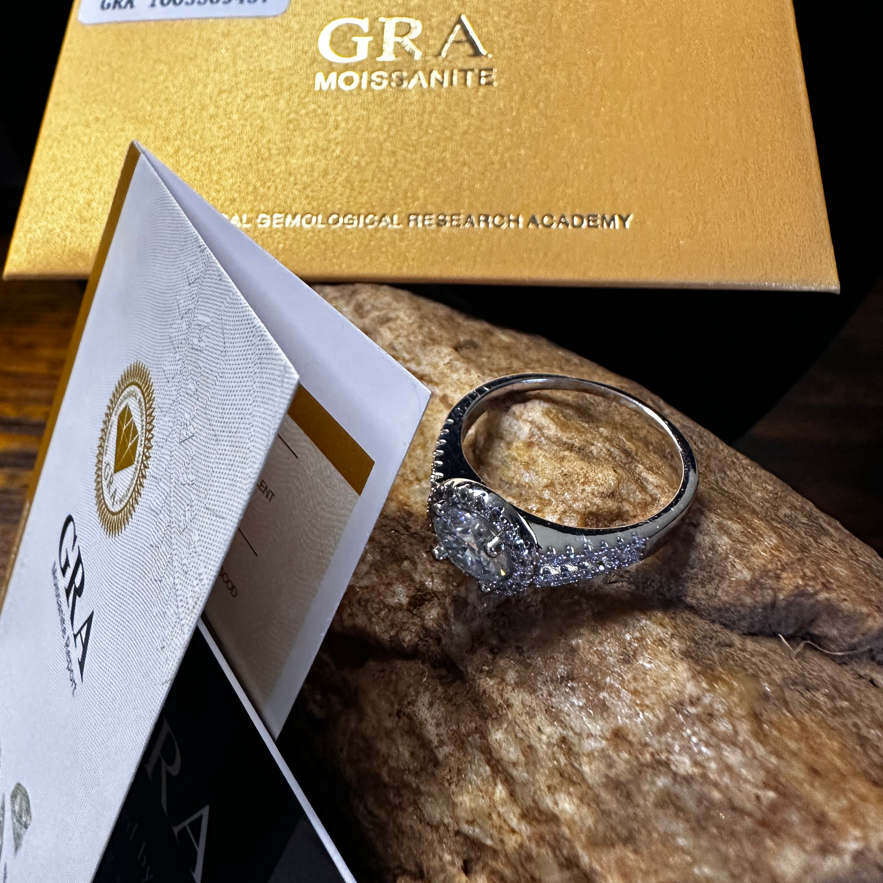 Silver ring on a rock with a gold box labeled 'GRA' in the background