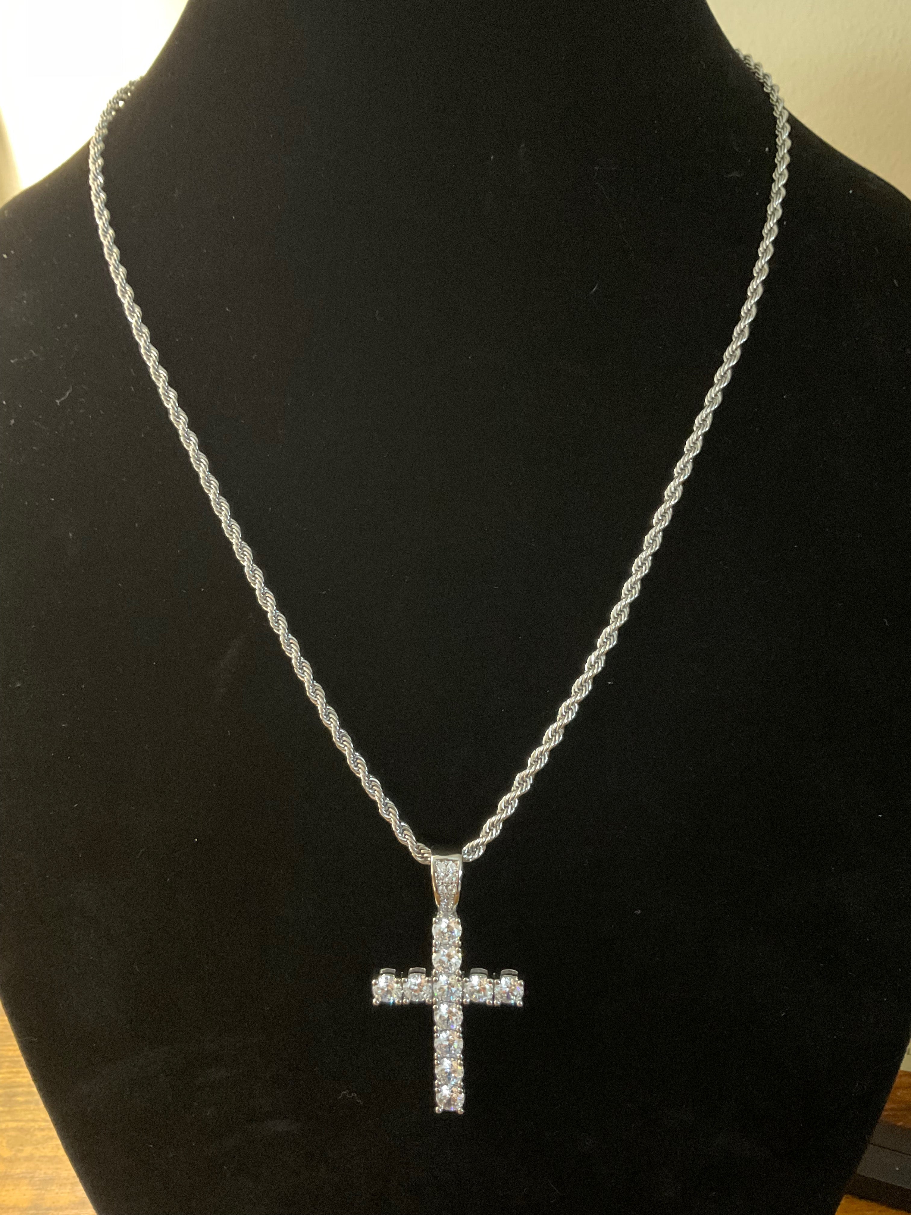 Silver cross necklace on a black mannequin