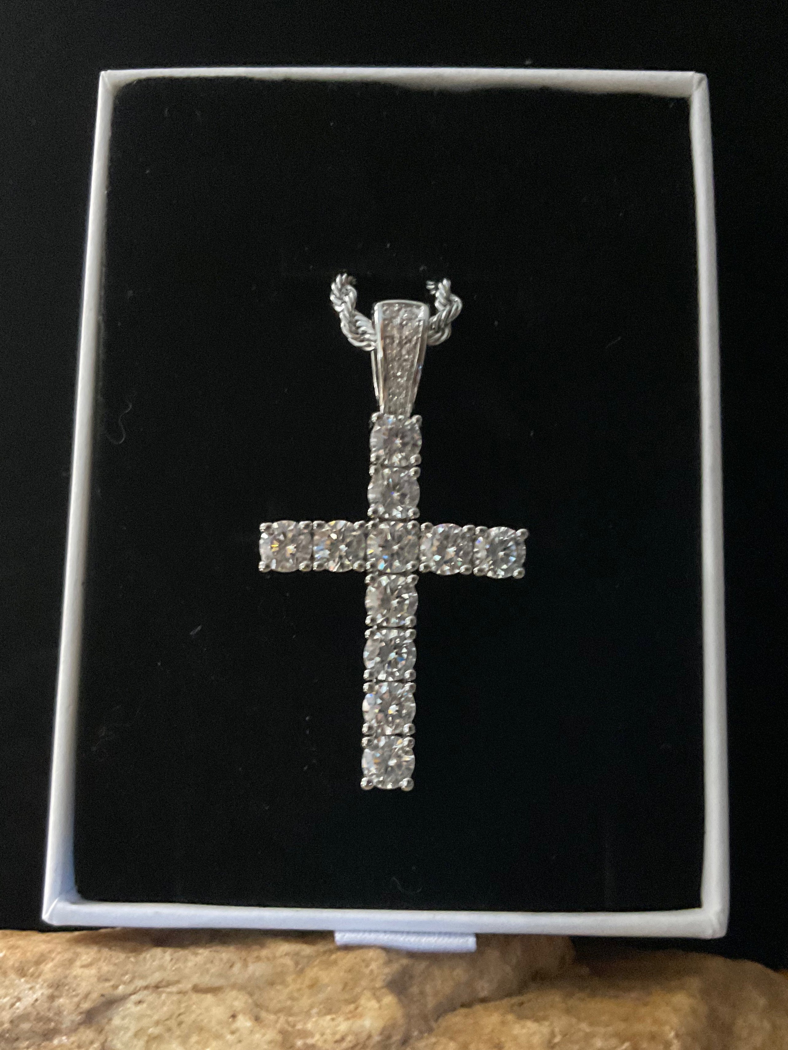 Silver cross pendant with intricate design on a black background
