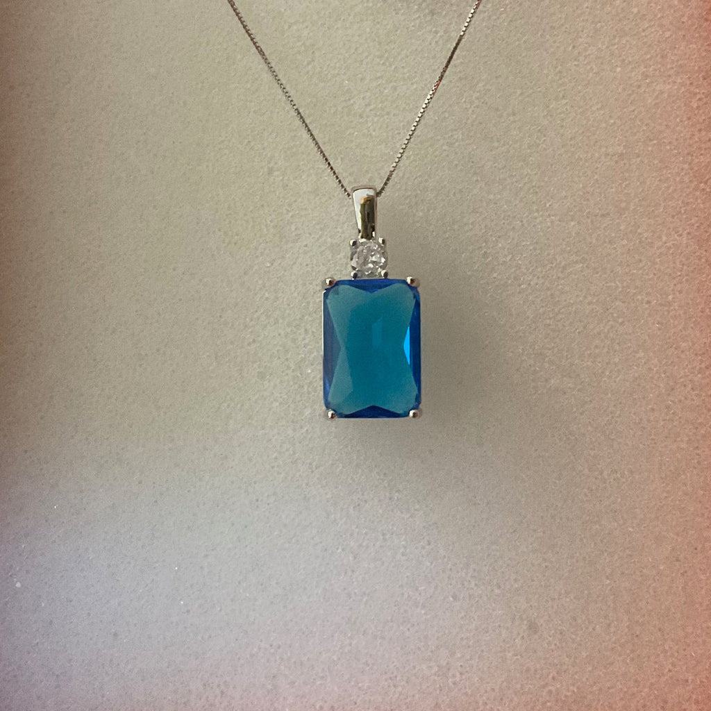 Blue pendant necklace in an orange box with a label