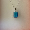 Blue pendant necklace in an orange box with a label