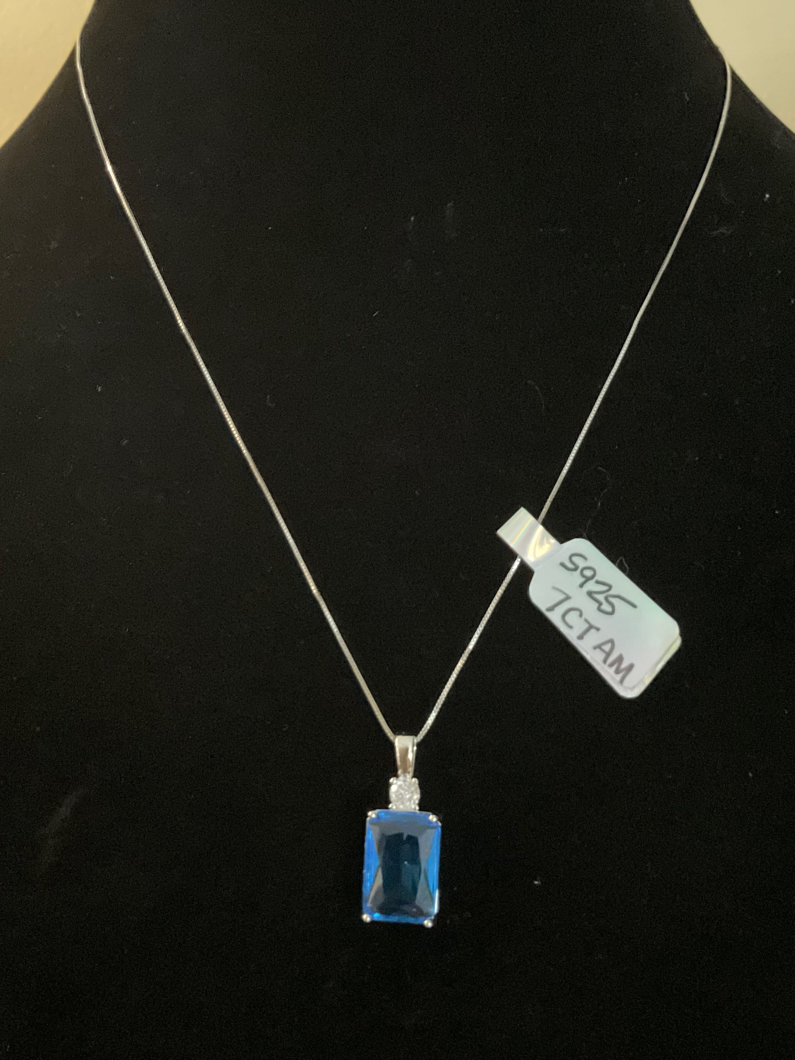 Necklace with a blue pendant on a black mannequin bust.