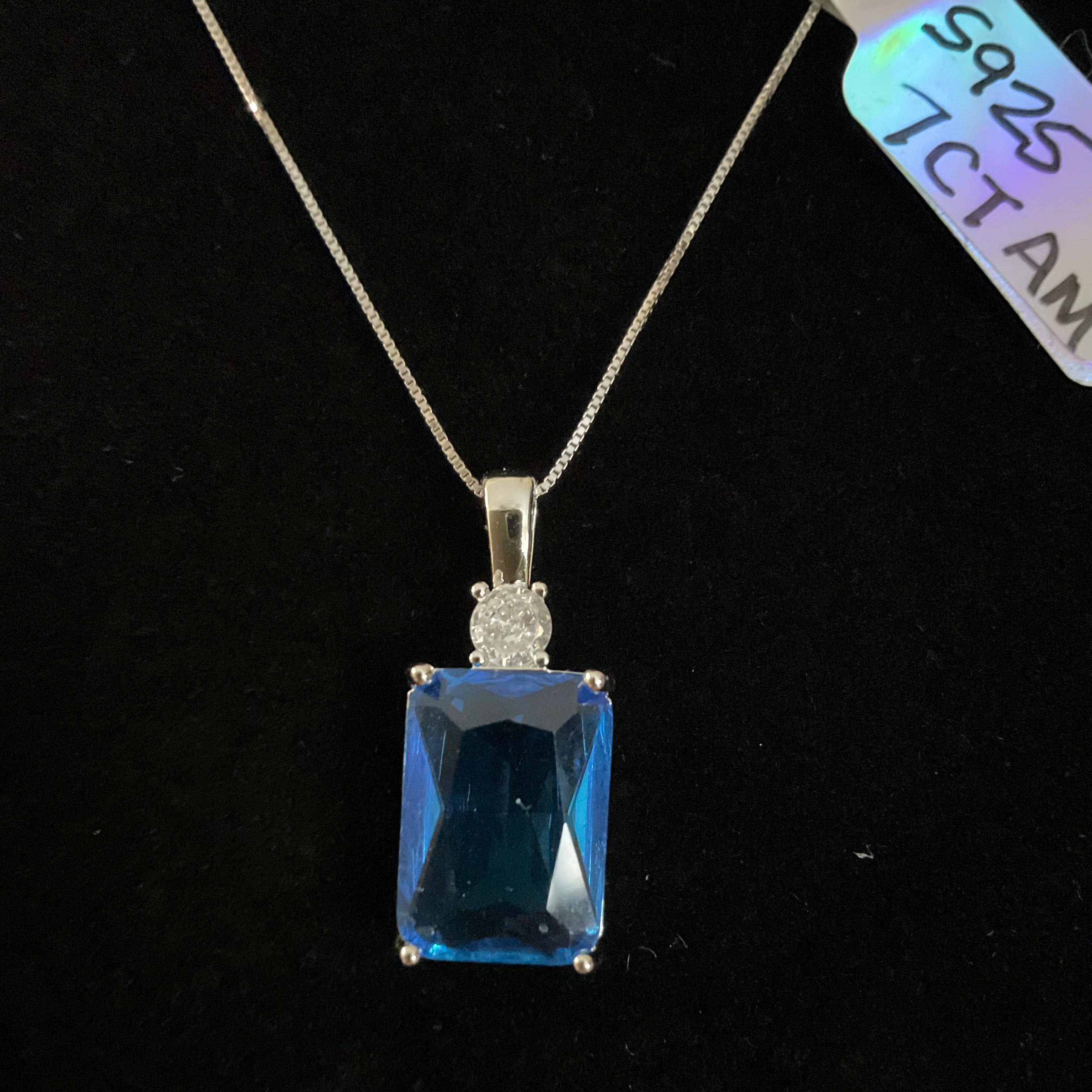 Blue gemstone pendant on a chain against a black background
