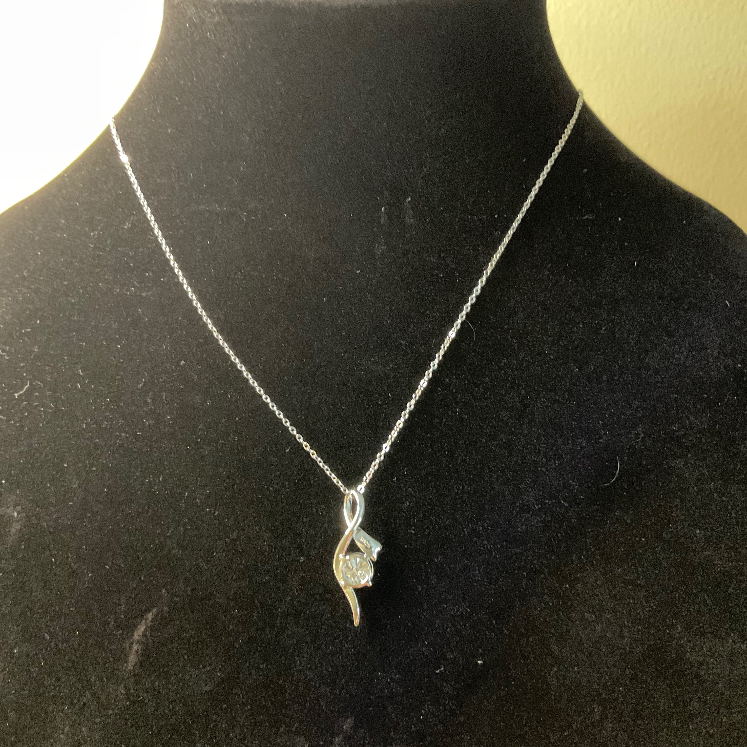 Silver necklace with a pendant on a black mannequin bust.