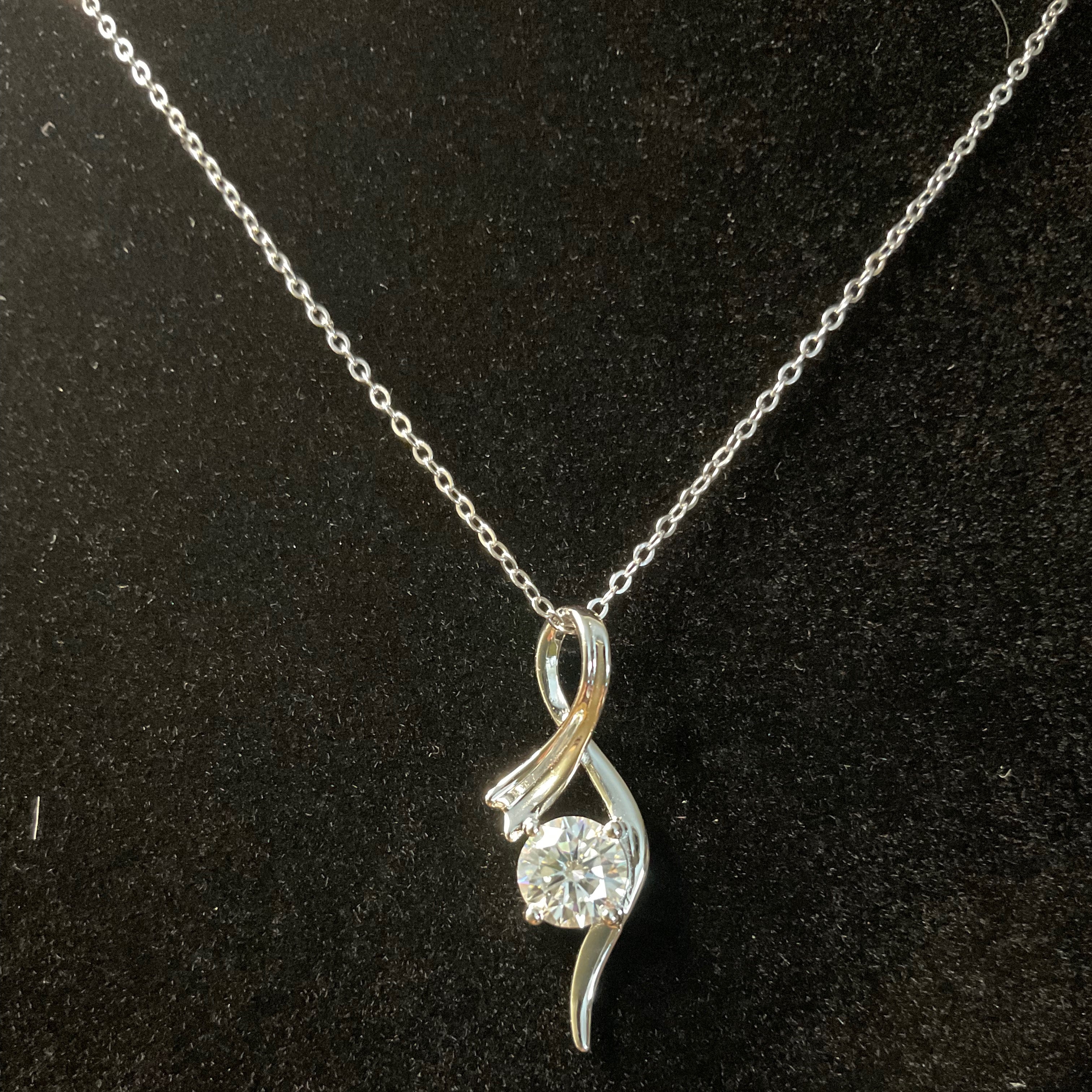 Silver pendant with a diamond on a black background