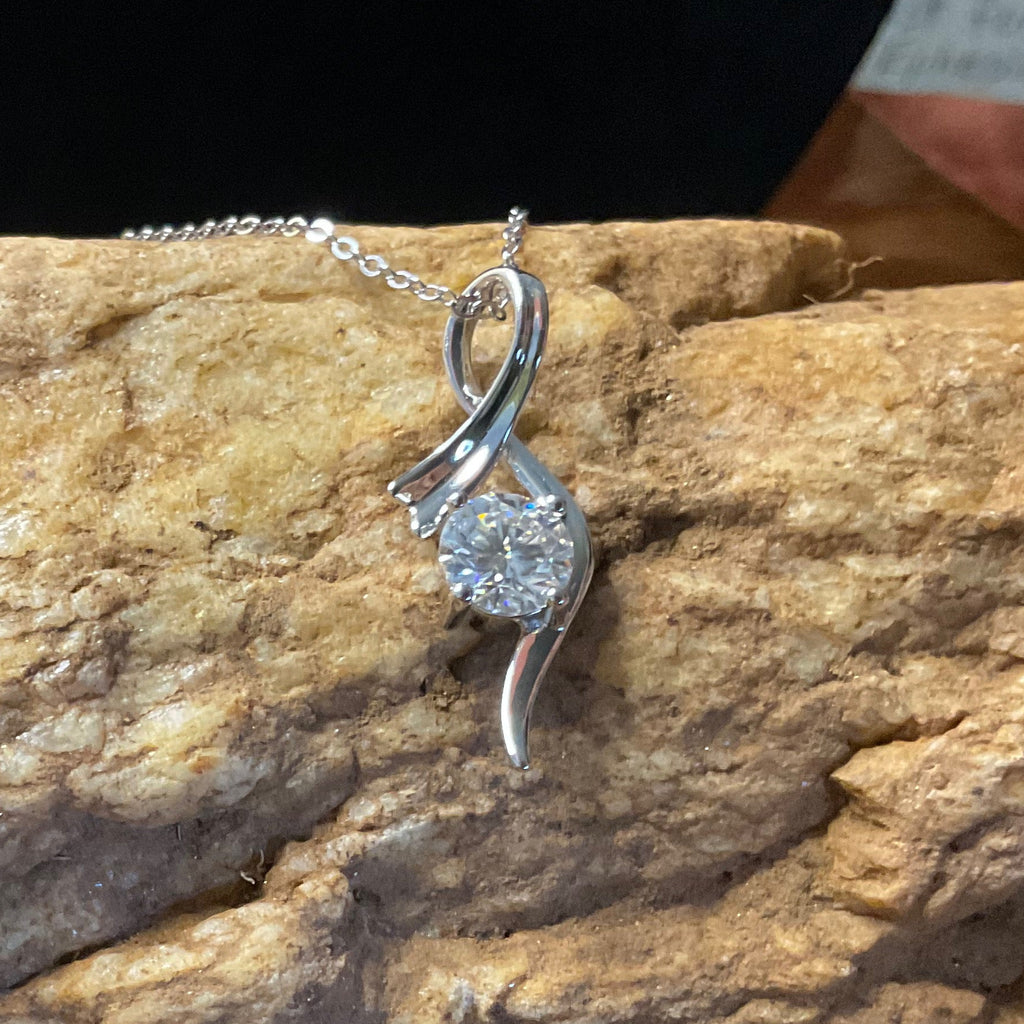 Silver bracelet with a diamond pendant on a textured rock surface