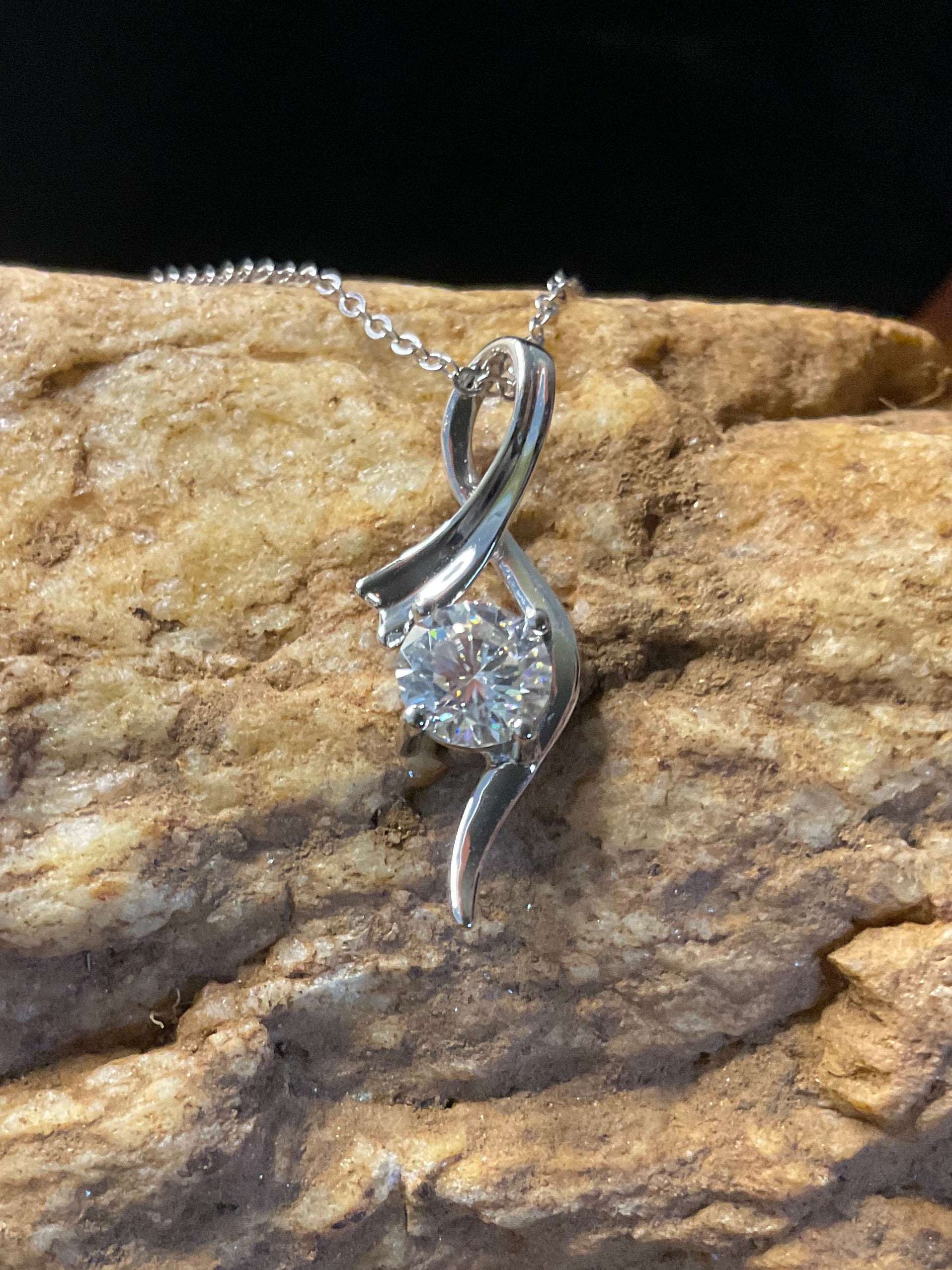 Silver necklace with a pendant on a textured rock surface