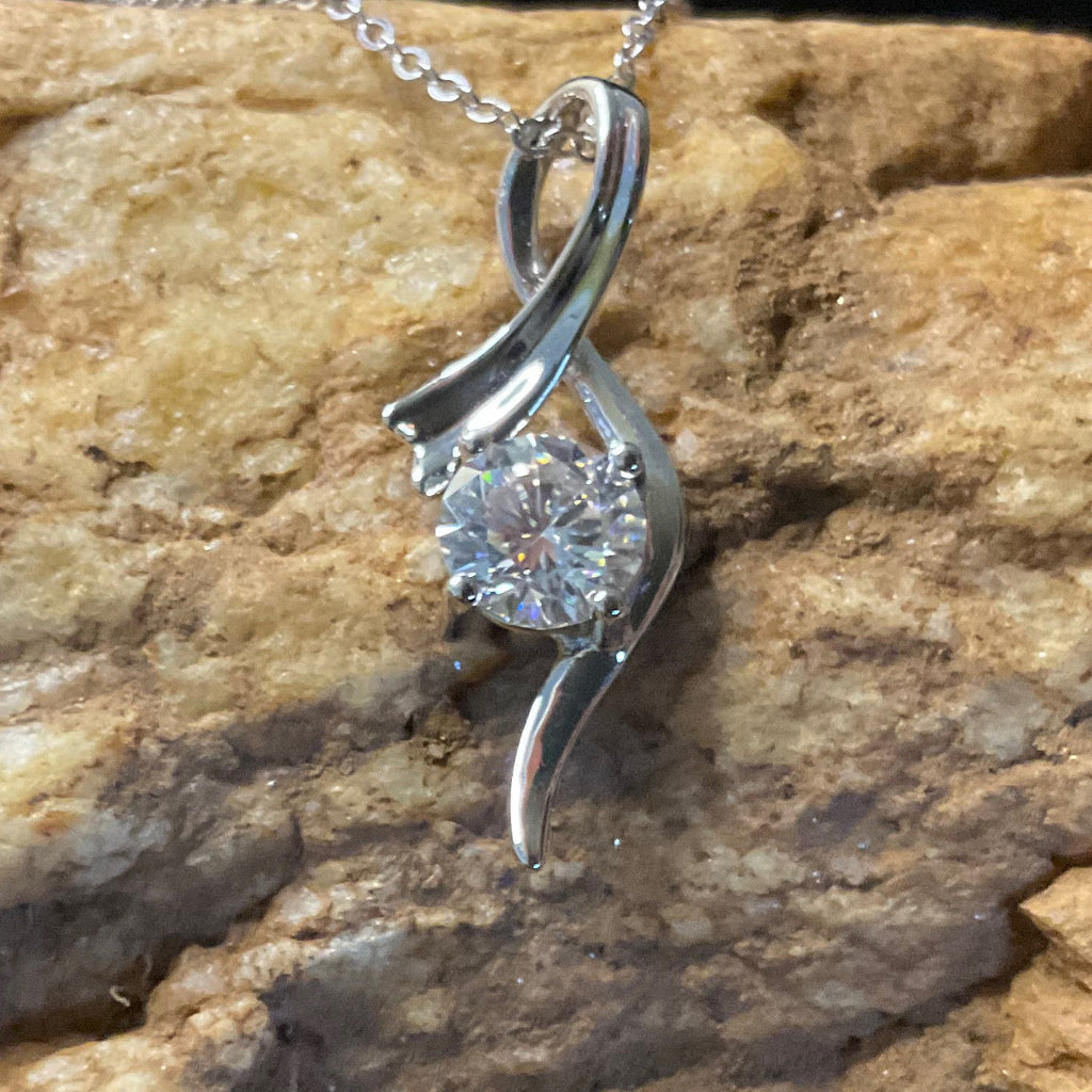 Silver pendant with a diamond on a textured stone surface